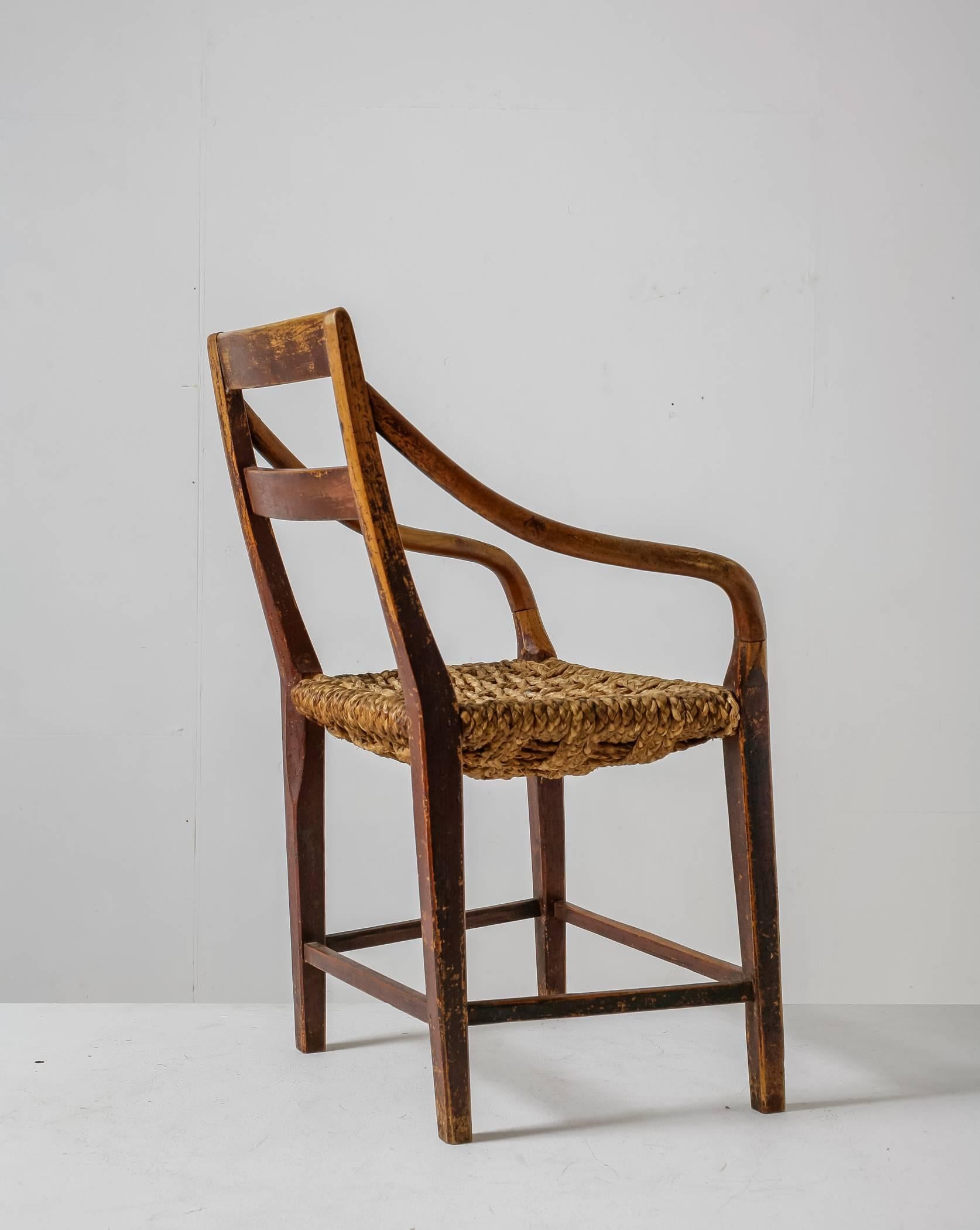 A 19th century armchair made of a stained beech frame with a seating made of thick woven raffia rope. The combination of the rugged seating and the thin and elegant curved armrests makes this a very interesting and unique object chair.

