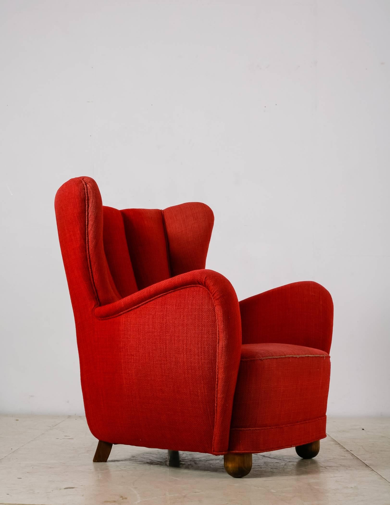 A Danish highback easy chair in the manner of Flemming Lassen. The chair has stained beech legs, round in the front and rectangular in the back. The chair is upholstered with original handwoven red wool, which is still in a good condition.
An