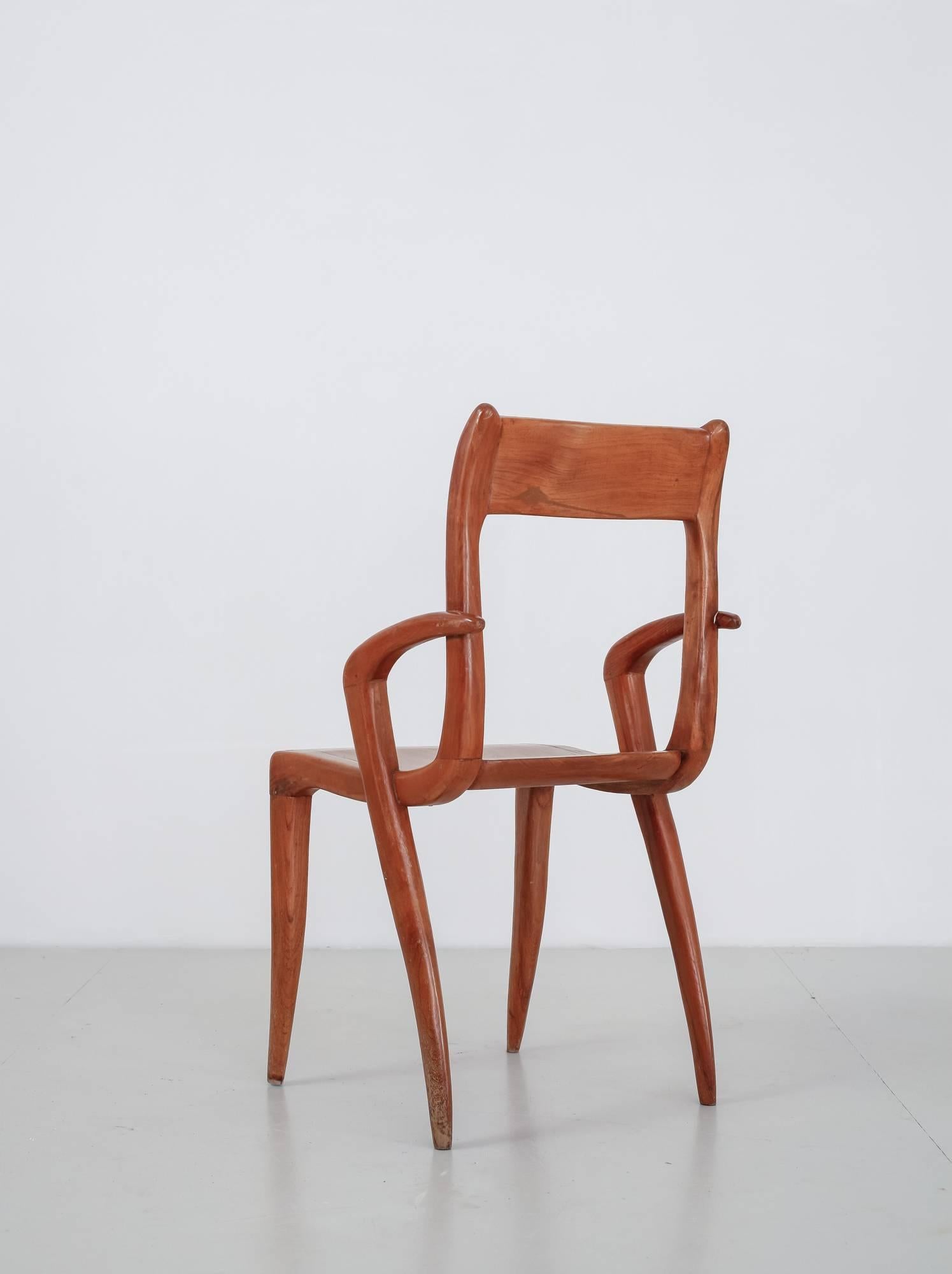 A Mid-Century American wooden craft armchair with an organic shape, reminiscent of the work of Arthur Espenet. The chair has saber legs of which the ones in the back extend into the armrests.
 