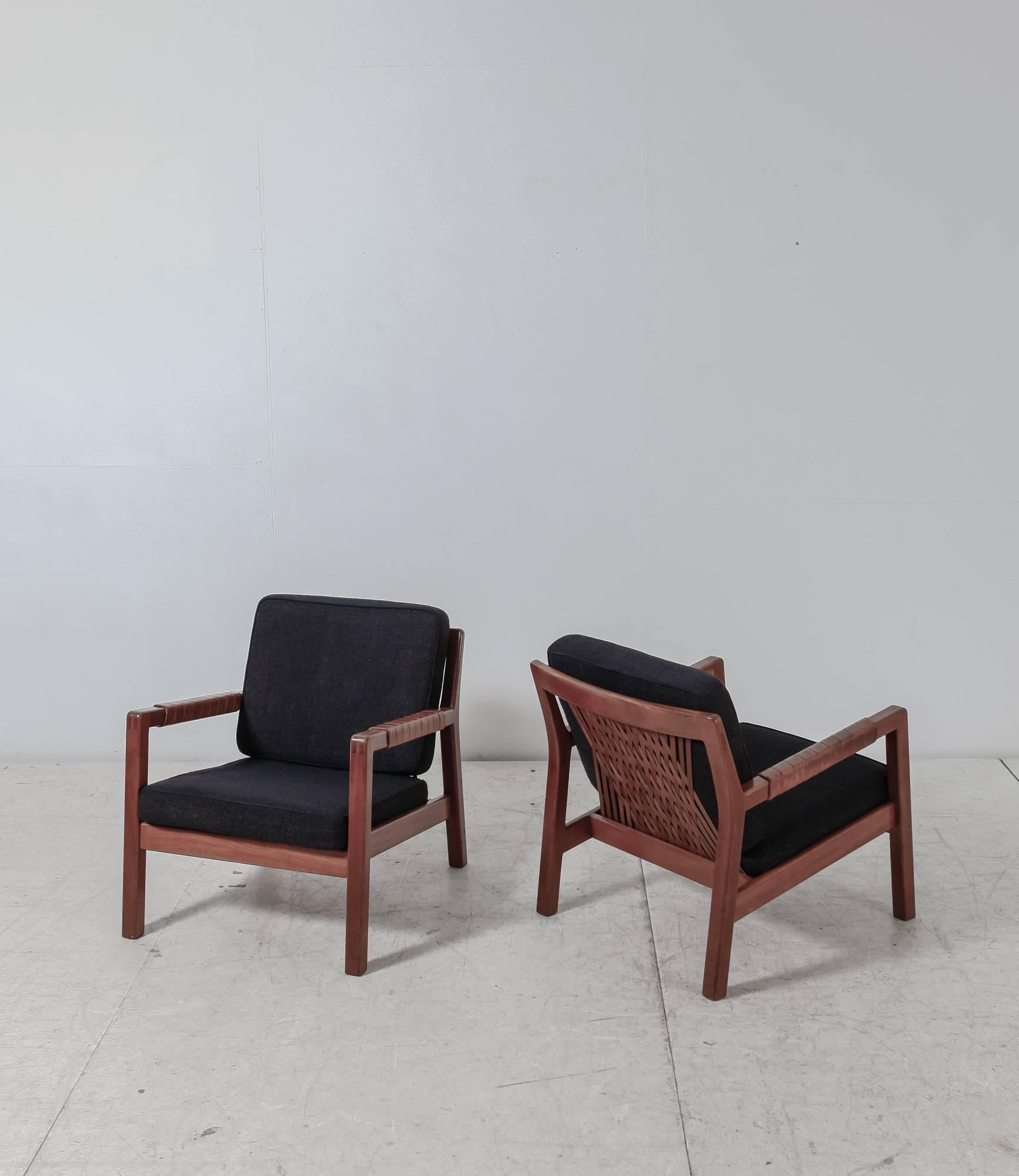 A pair of Carl-Gustav Hiort af Ornäs model 'Trienna' armchairs with fabric cushions. The backrest is made of a beautifully webbed leather. The frames are made of oak with leather wrapped around the armrests. The leather has a beautiful patina.
  