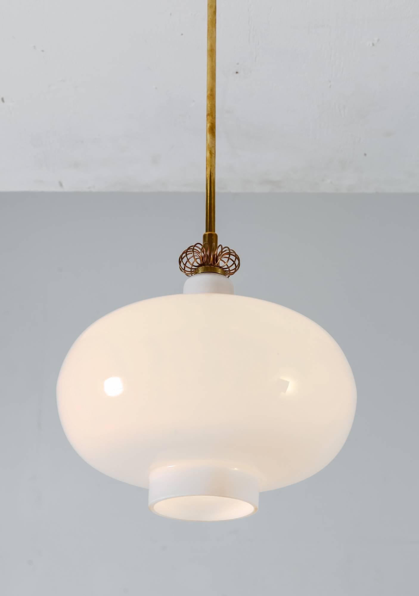 A very rare Paavo Tynell model 'K2-19' pendant for Idman, Finland. The lamp is made of a bell-shaped opaline glass shade with a brass celing stem and decoration.

