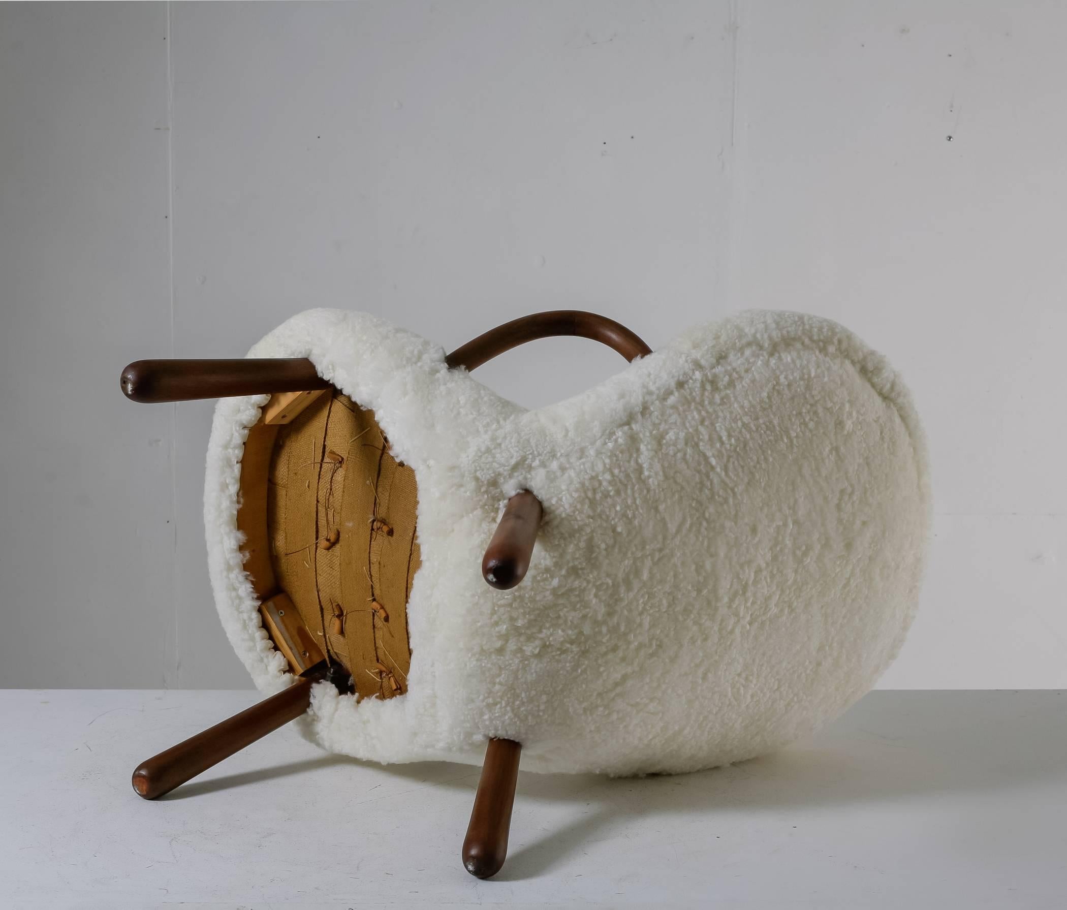 A Musling (clam) chair by Philip Arctander. The chair is made of a lacquered beech frame and a newly upholstered with a white sheep skin. The wooden armrests are molded and the legs are rounded, giving the chair an organic shape and the inspiration