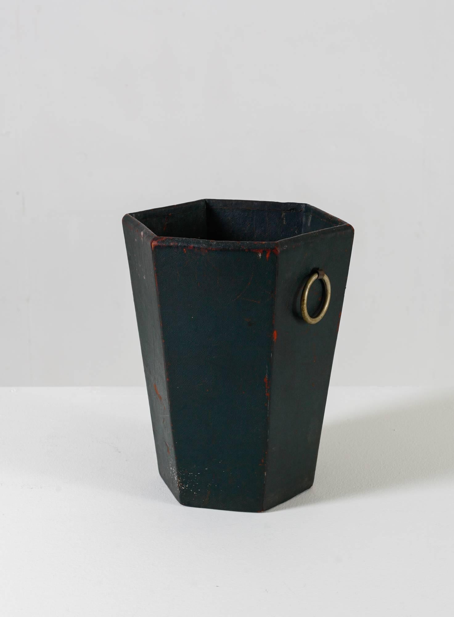 A hexagonal waste basket by French designer Jacques Adnet. The basket is made of green leather over a wooden frame, with two brass handles.

This luxurious piece has a strong patina, adding to its beauty.