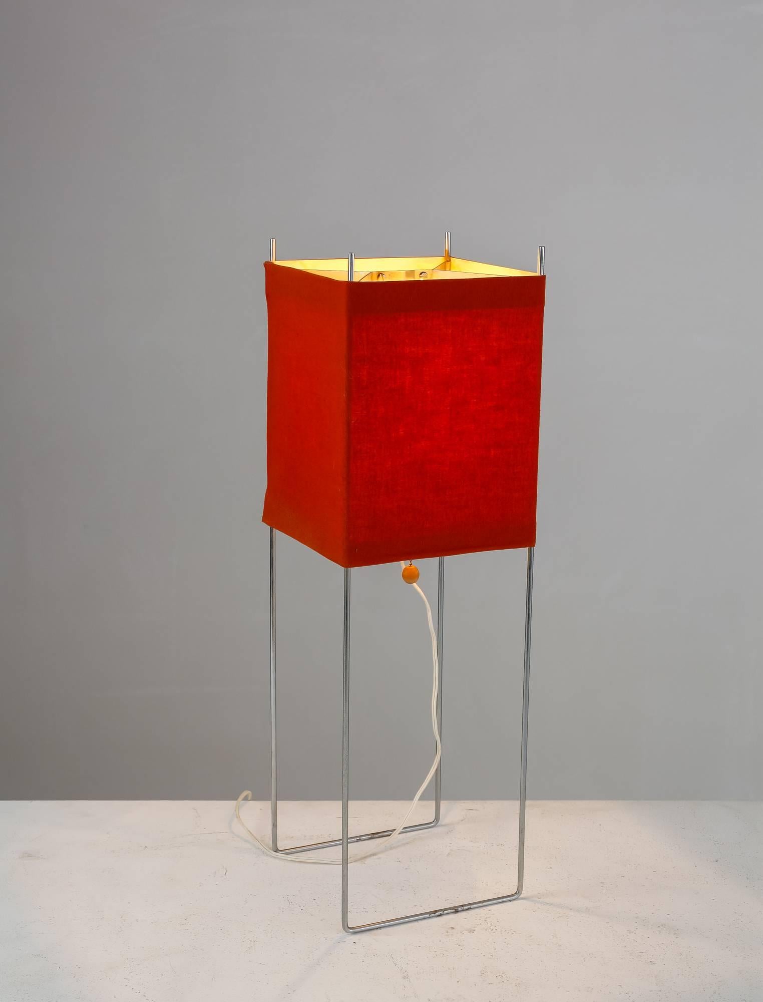 A George Nelson 'kite' table or floor lamp. The lamp is made of a chrome-plated metal frame with a red fabric diffuser wrapped around it. It has a pull chain switch with a wooden ball.