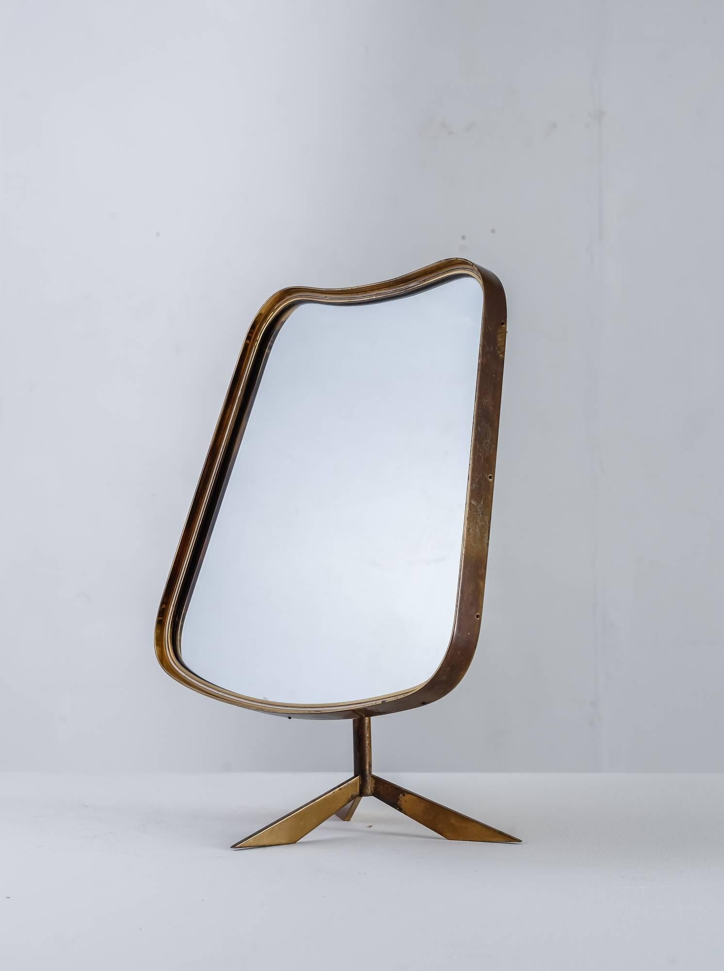 An adjustable brass console mirror with a curved frame on a tripod foot. 
The mirror can be positioned with the concave side of the frame up or down.