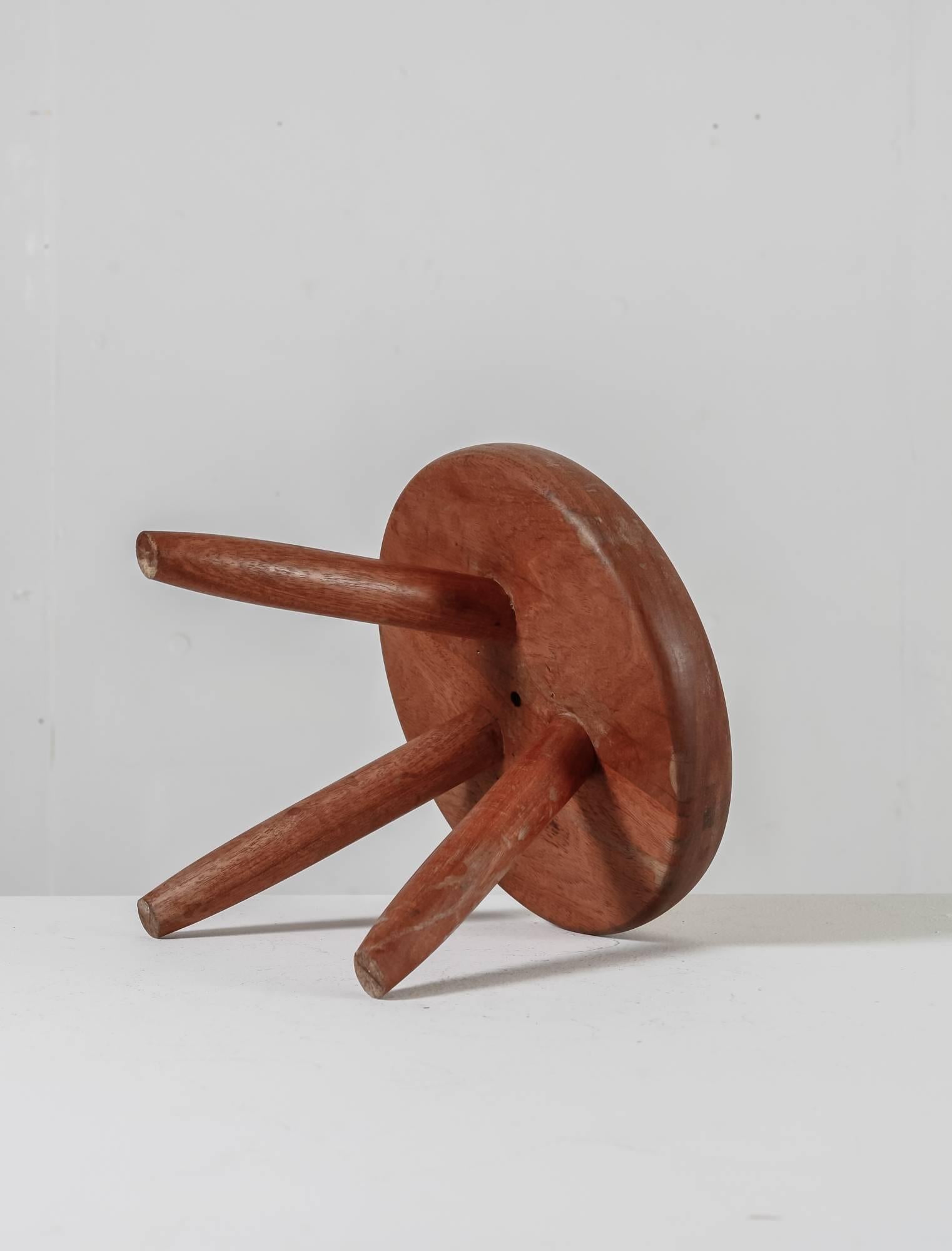 A low tripod stool by Charlotte Perriand in teak. The stool has beautiful wood connections and the teak has a great patina.