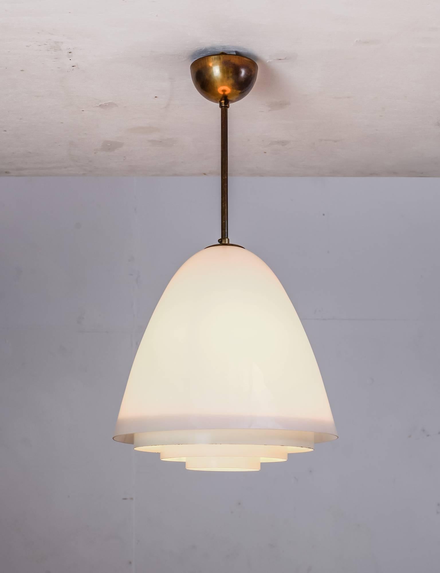 A rare finish pendant made of a bell shaped opaline glass shade with a white lacquered metal grid underneath. The lamp is connected to the ceiling with a brass stem.
A stunning, minimalistic design and the lamp is in a great, original condition.
 