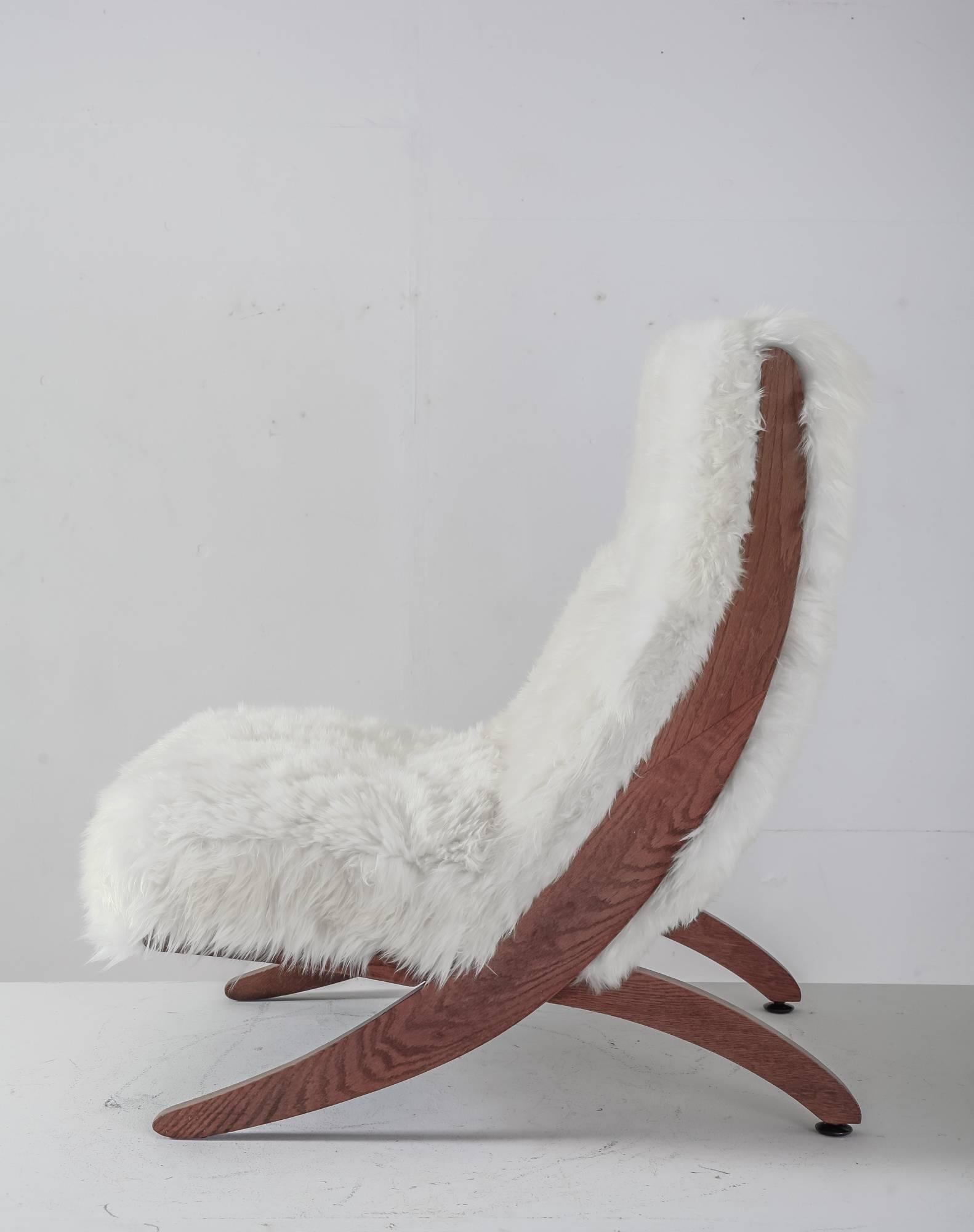 A 1950s oak lounge chair consisting of two interlocking pieces. The back legs stand on small metal feet. This chair was professionally reupholstered with a double layered white sheepskin.

An unique and very comfortable chair in a great condition.