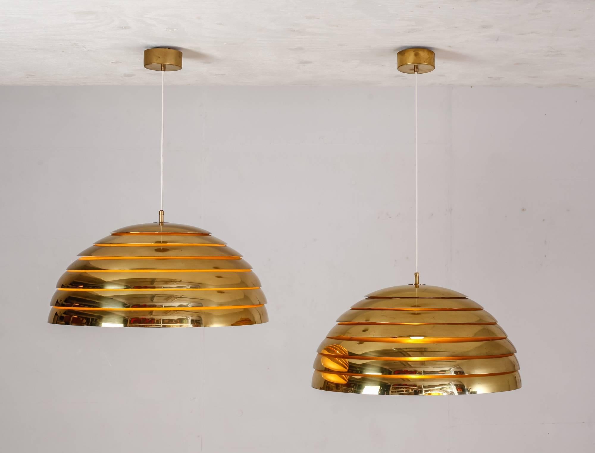 A pair of beautiful late 1960s-early 1970s large brass pendant lamps from Germany. The pendants are made of seven brass rings with a plexiglass diffuser and are in a perfect condition.
The combination of the soft downwards light and the warm glow
