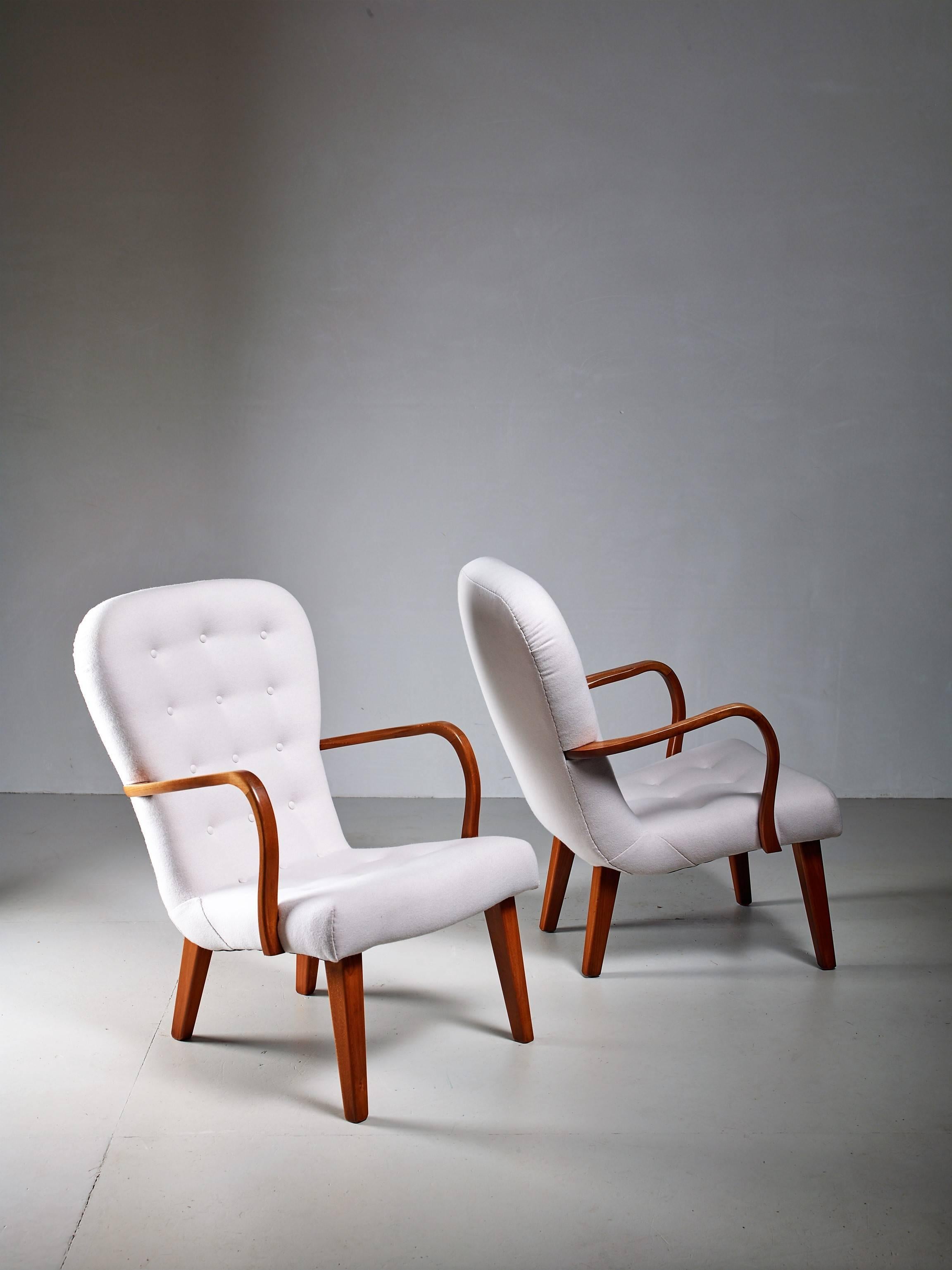 A pair of Danish lounge chairs with a curved frame of stained beech and an off-white wool felt upholstery. The sculpted arm rest have two different levels, for a comfortable seating position.
The chairs have been professionally reupholstered in our