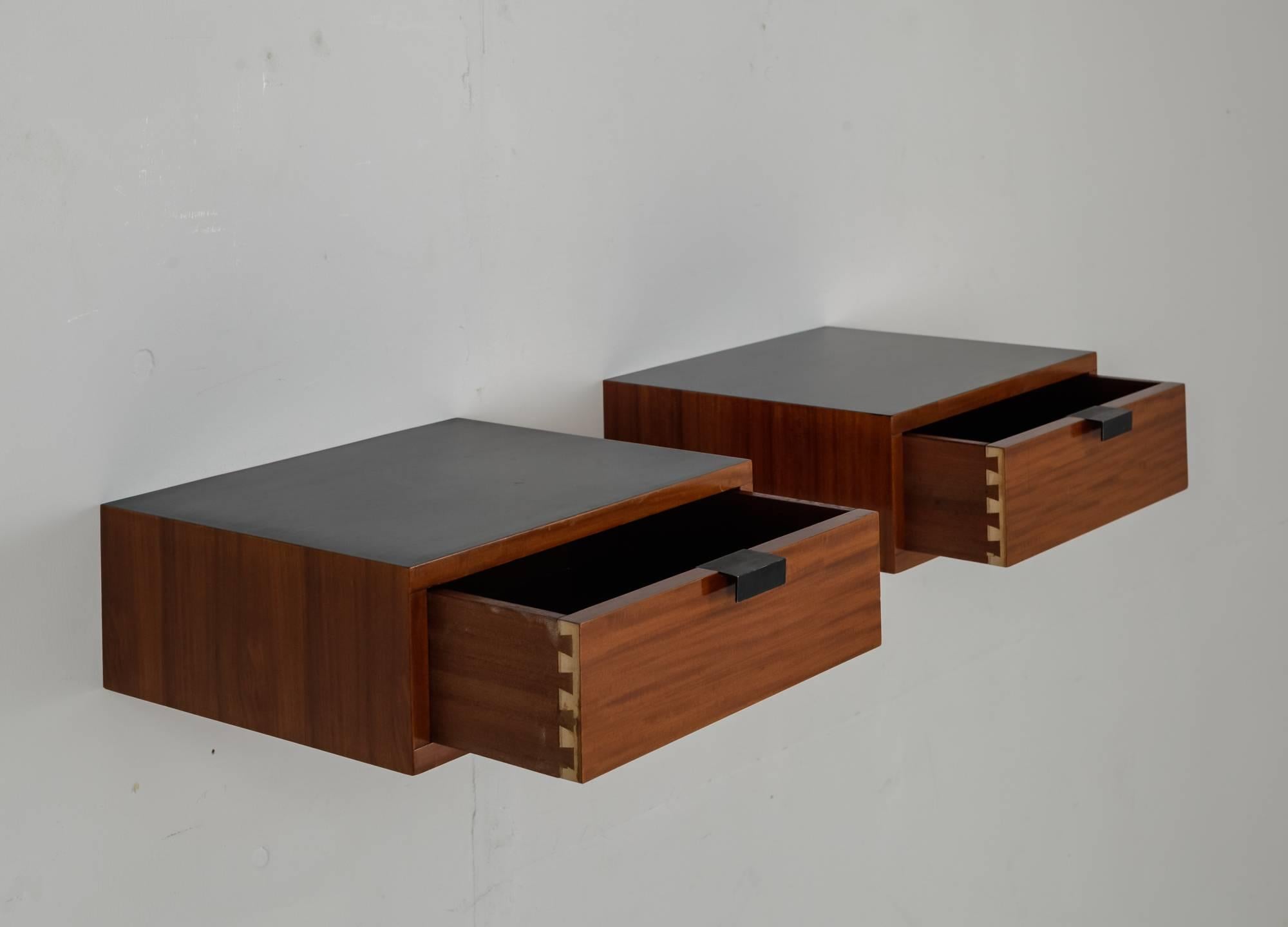 A pair of wall-mounted cabinets with one drawer, designed by Pierre Paulin for Thonet. These pieces are made of wood with a black lacquered top and metal pulls.