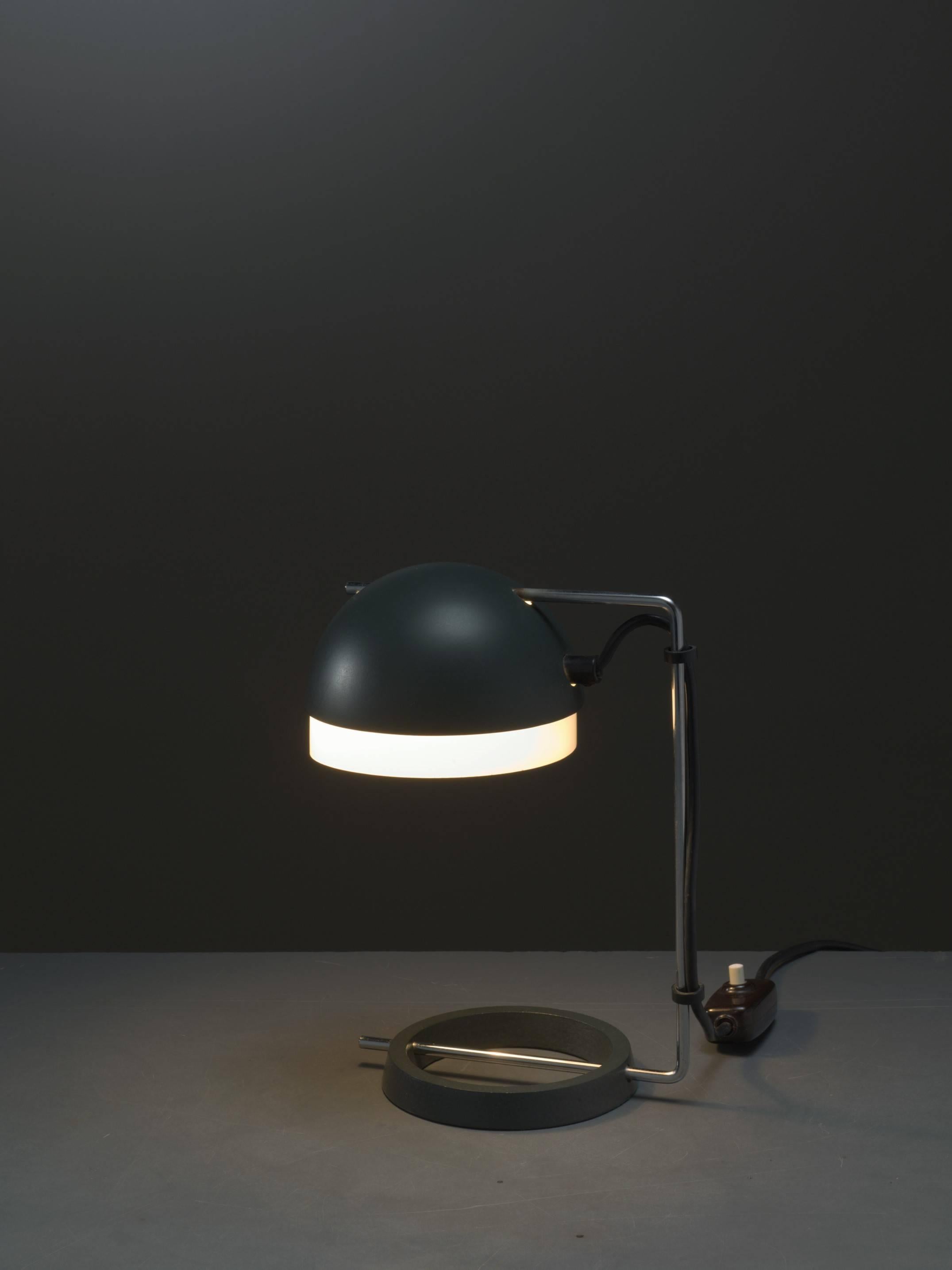 A rare, adjustable desk lamp by Swiss designers Rosemarie and Rico Baltensweiler.
The lampshade is made of dark green metal, with a white plastic inlay, held by a chrome bar in a U-shape. The foot ring is made of solid dark green metal.
Both the