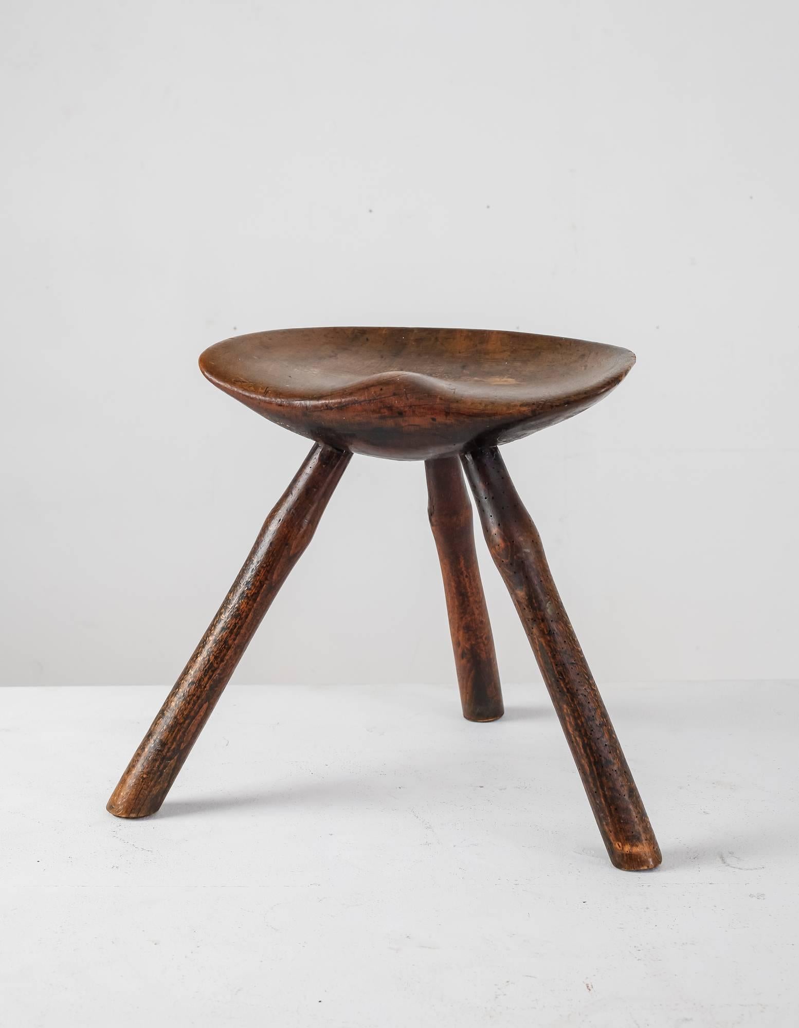 A Danish Folk Art tripod stool made of oak. The stool has a beautiful, sculpted seating (38.5 cm/15