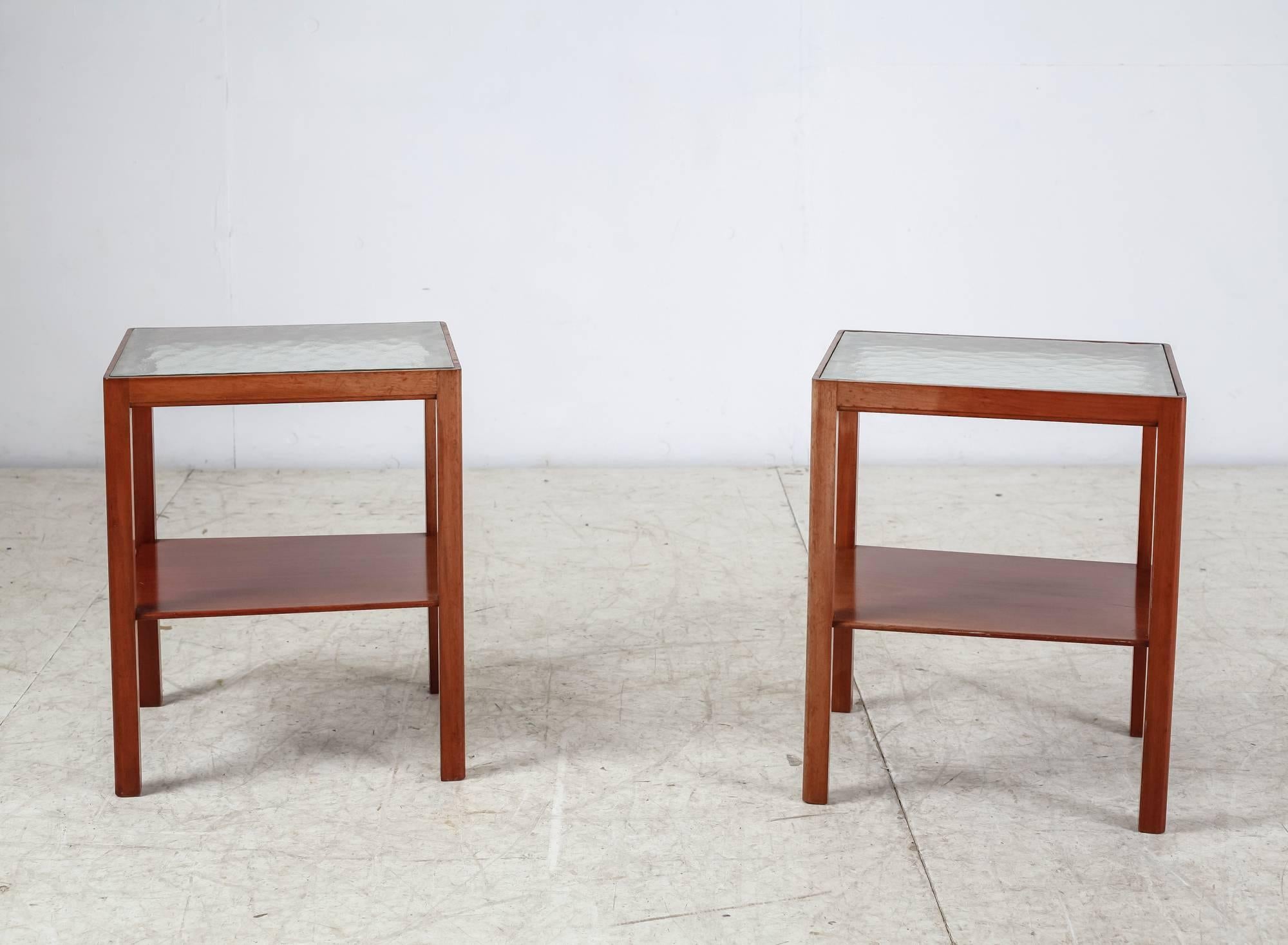 A pair of end or side tables by Danish cabinetmaker Thorald Madsen. They are made of a rounded Cuban mahogany frame with a top of beautiful old, textured glass. There also is a mahogany shelf underneath.
Labeled by Madsen and in a wonderful
