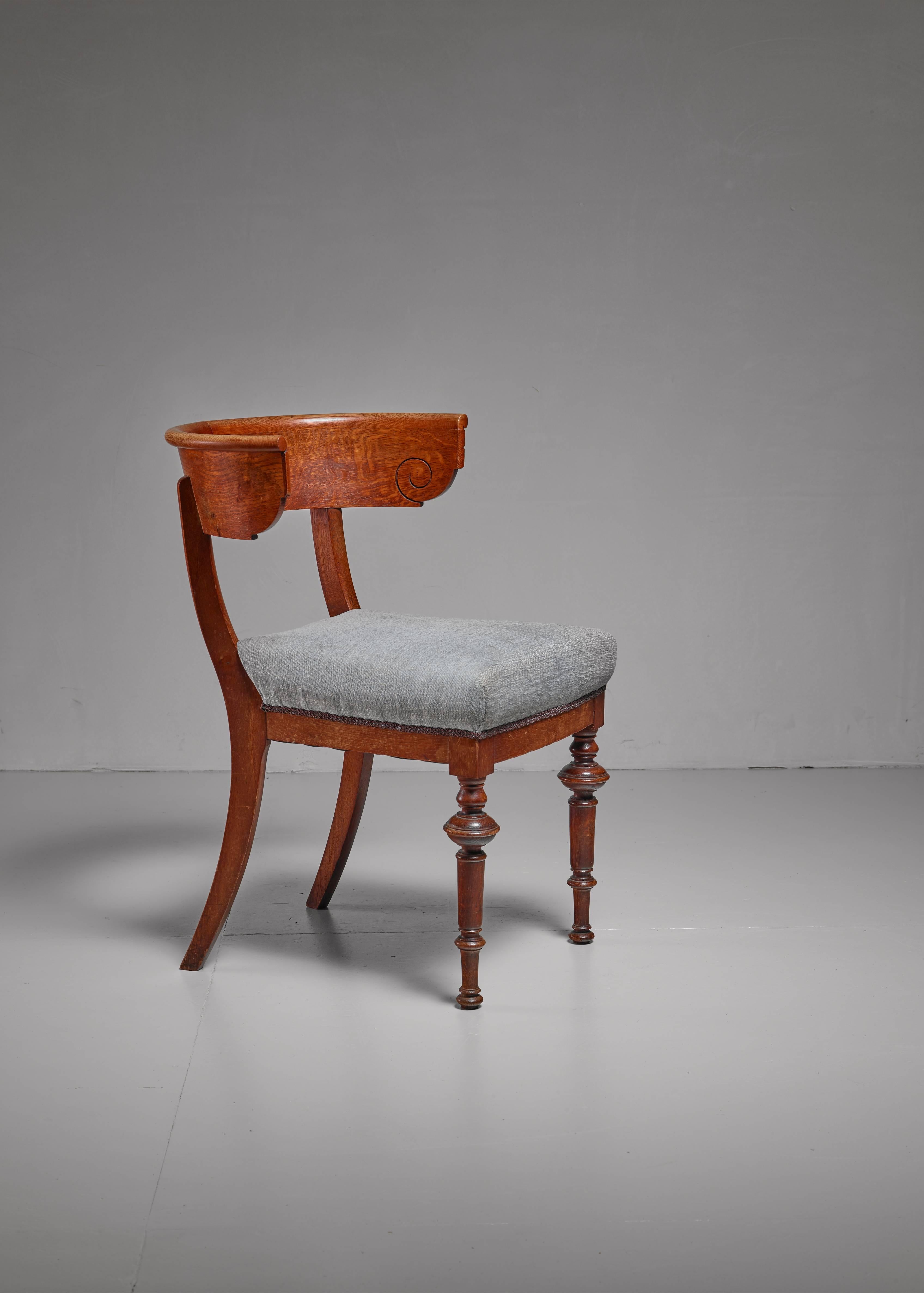 An early 20th century Danish Klismos chair made of oak with sculpted front legs and sabre back legs and has a blue grey fabric upholstery. The chair has been professionally reupholstered in our in-house atelier.
 