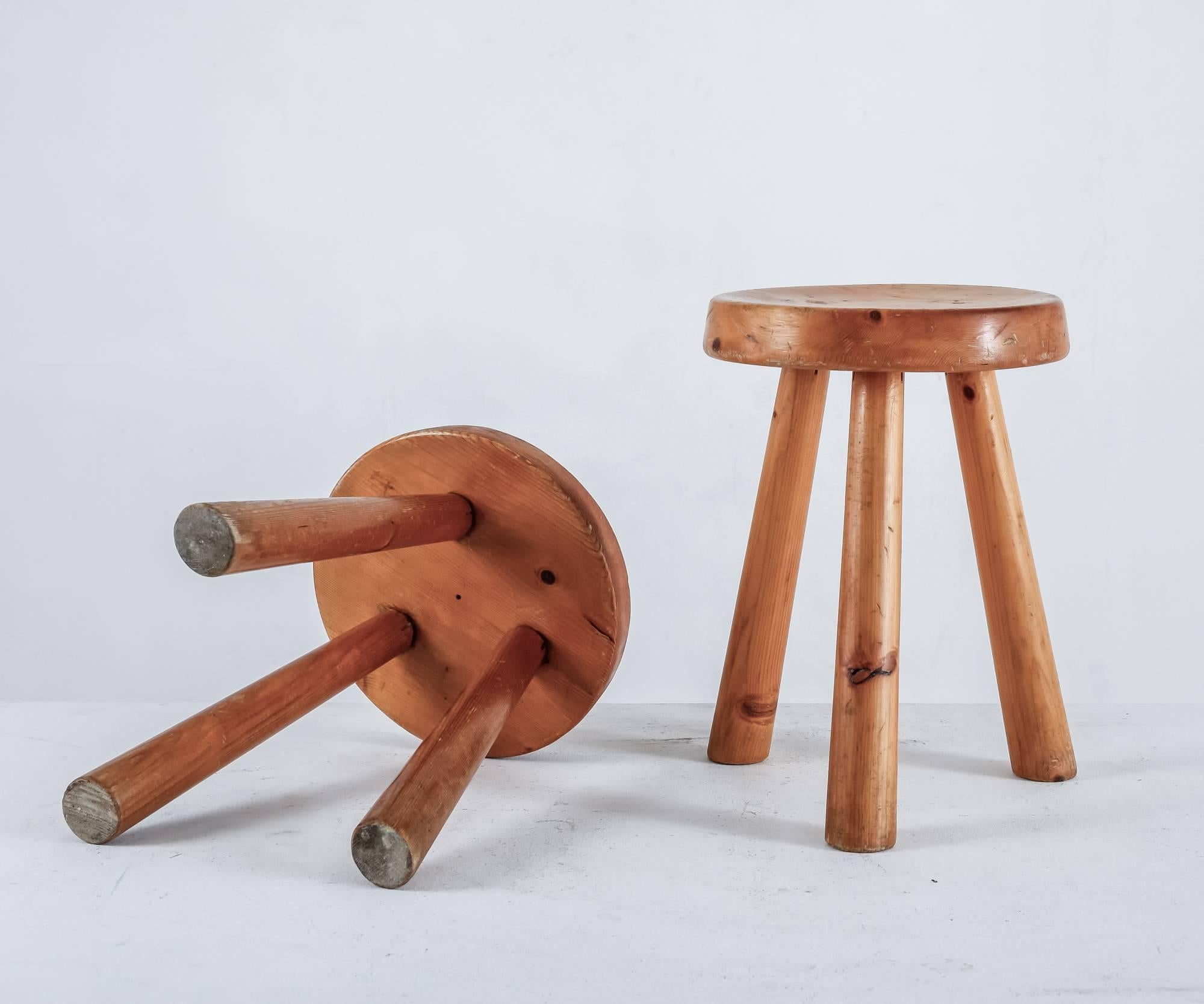 A pair of tripod pine Charlotte Perriand stools with a round seating with a diameter of 31.5 cm (12.5
