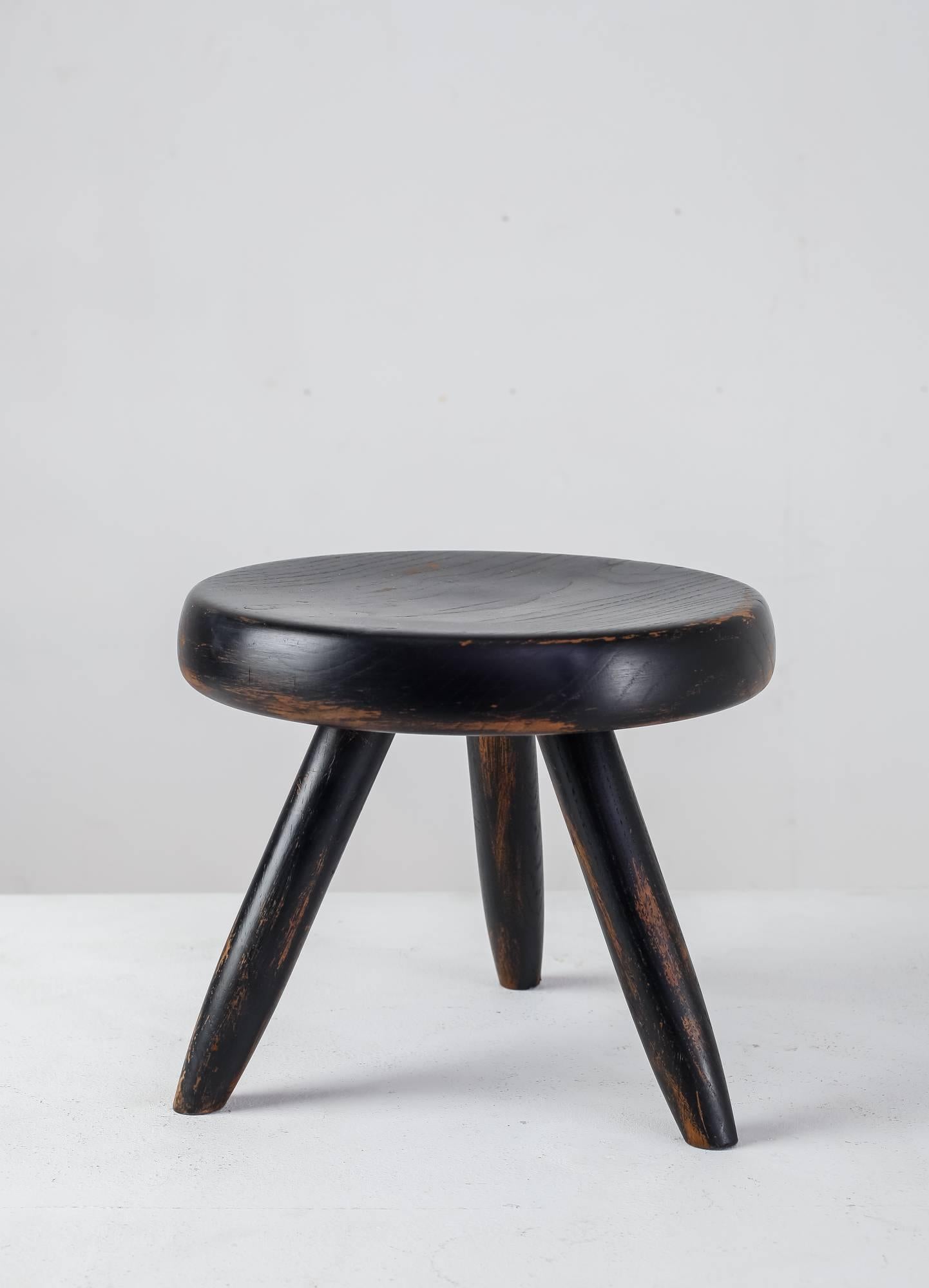 A low tripod stool in ebonized ash by Charlotte Perriand, with a great and strong patina.

The first tripod stool of this type by Perriand was designed in 1947 and produced by Georges Blanchon’s Bureau Central de Construction. In 1956 Perriand