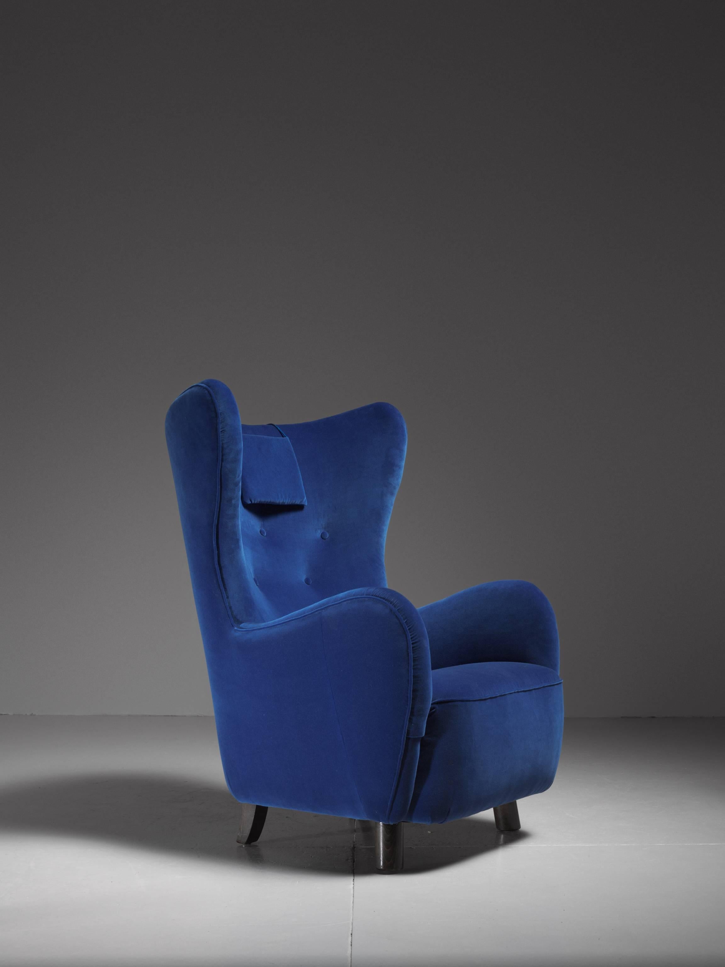 A 1940s wingback lounge chair attributed to Mogens Lassen. It stands on stained beech legs, round in front and rectangular in the back.
The chair has been professionally reupholstered in our atelier with a beautiful royal blue velour.
