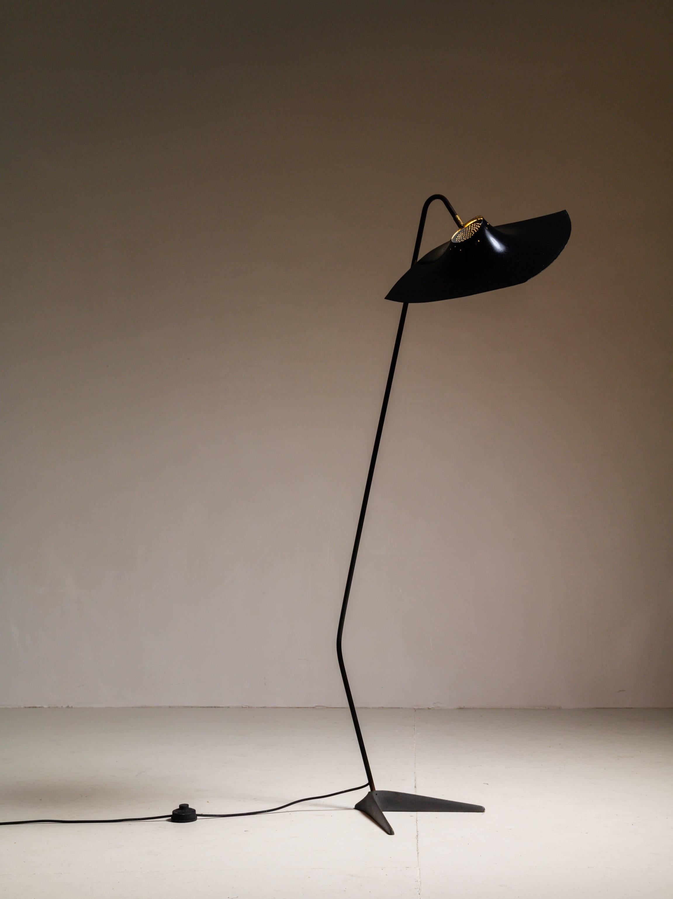 A unique Mid-Century French floor lamp. The black, bent iron stem holds a metal shade, that is connected with a ball-joint.
The curving metal shade has a shape that is reminiscent of a manta ray and is lacquered black on the outside and white