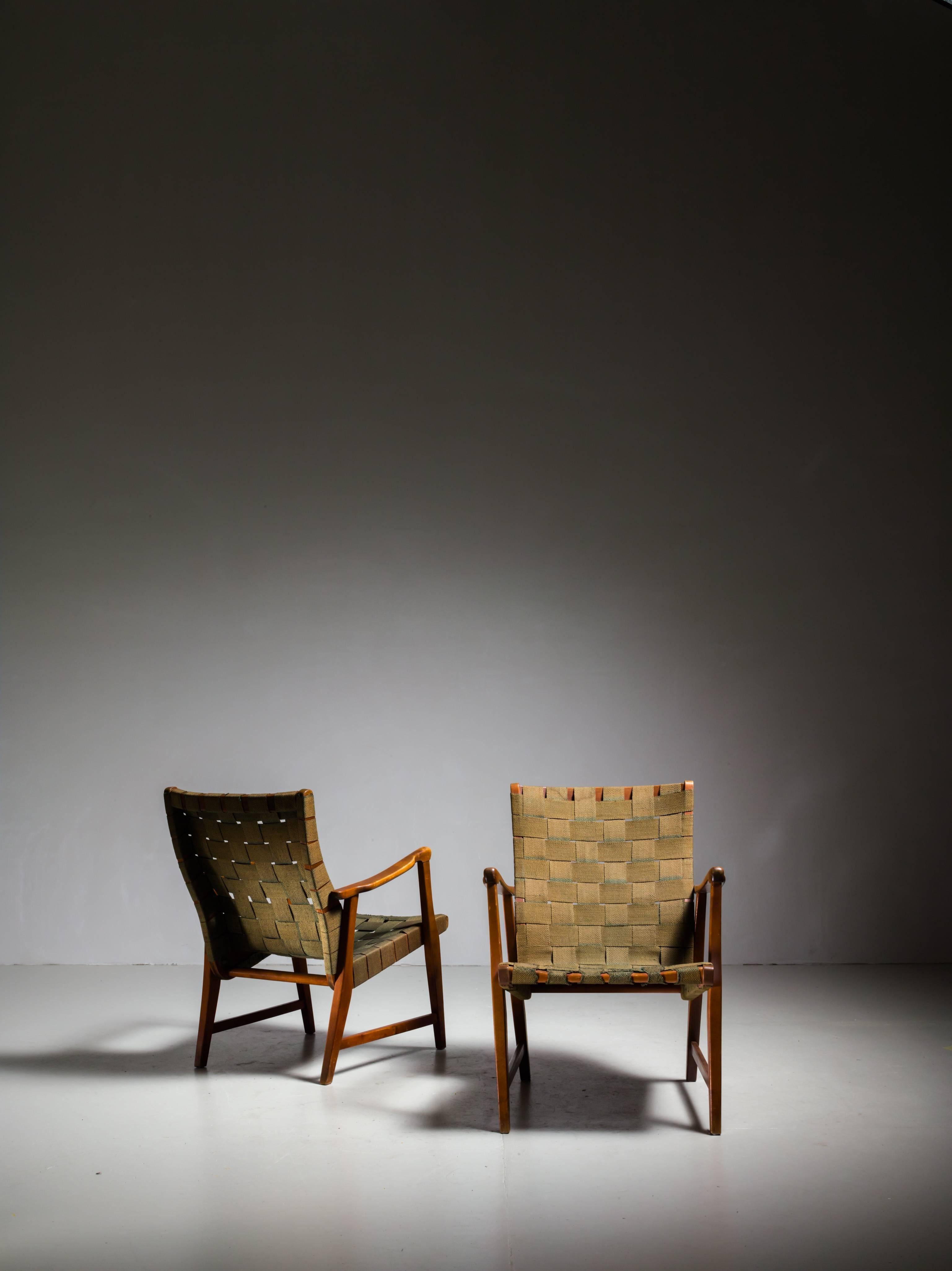 A pair of armchairs by Nordiska Kompaniet, made of a stained beech frame and a webbed dark green canvas seating.
The chairs are attributed to Elias Svedberg and still have the metal Nordiska tags.

The webbing shows wear at the edge of the
