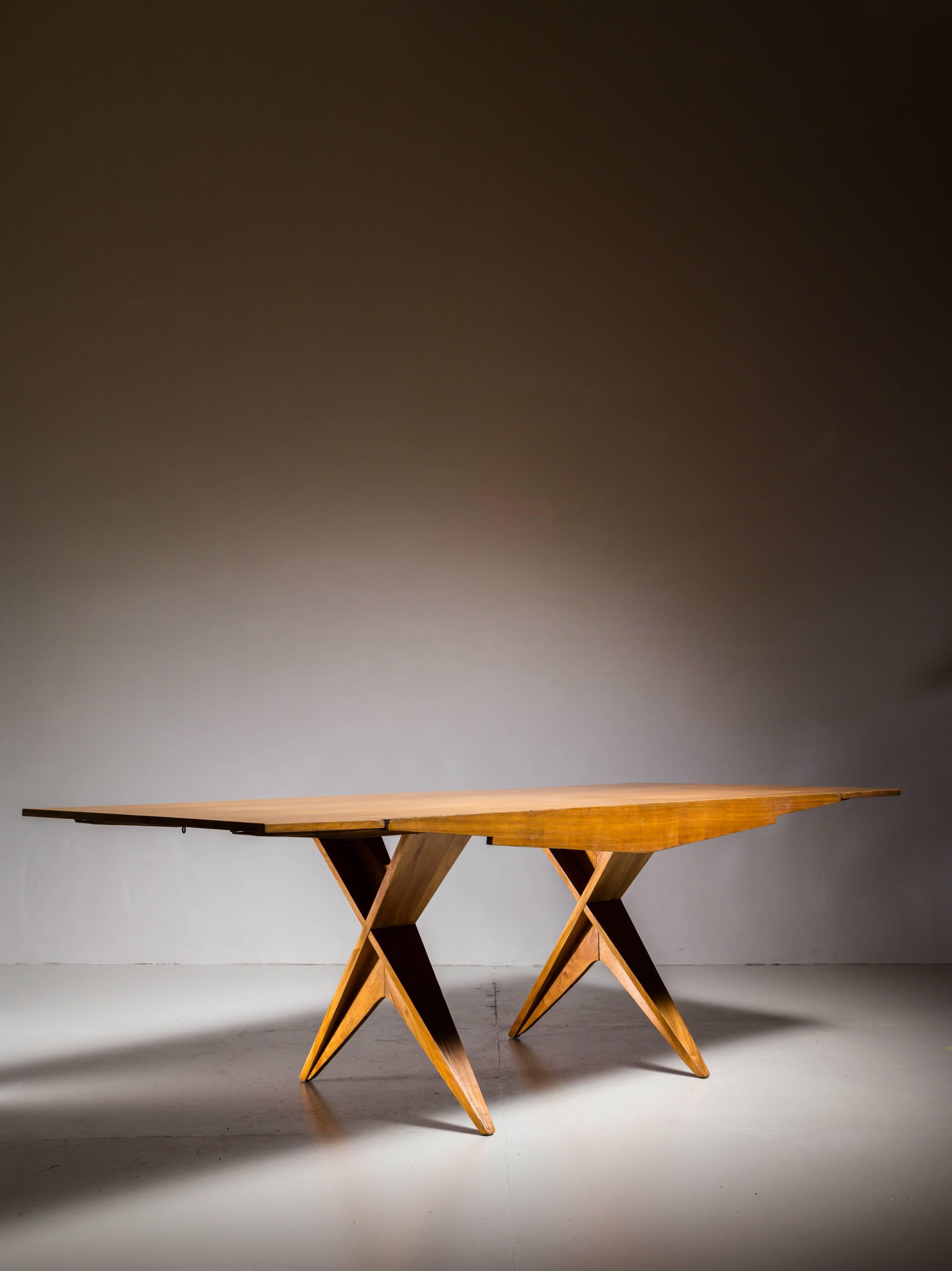 A blonde mahogany fold-out table on architectural X-base legs by Californian designer Dan Johnson. The extensions fold down and inwards and in both positions the dimensions and Silhouette of the table are in a perfect balance.

When unfolded the