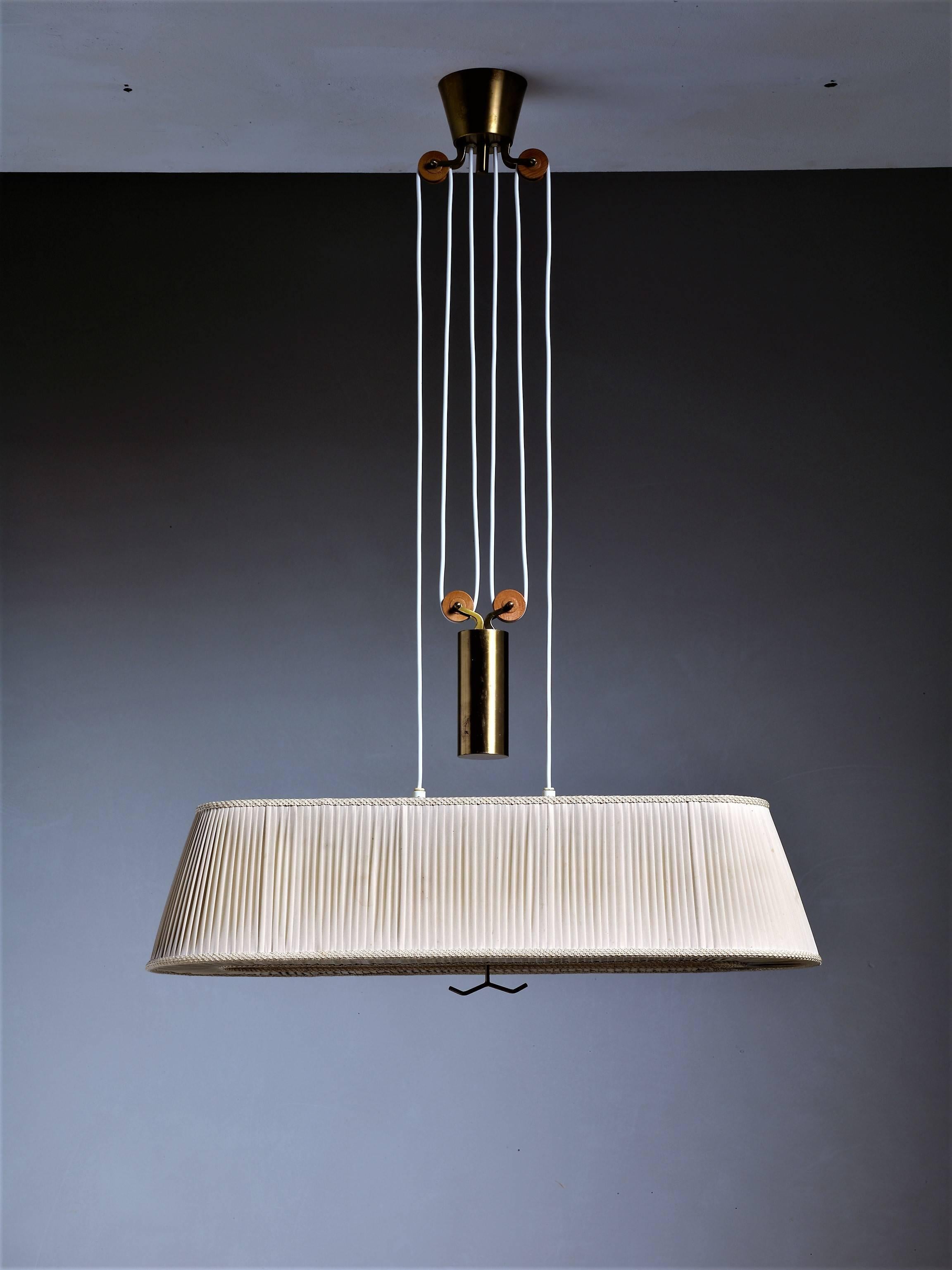 A rectangular, height-adjustable Swedish pendant with a heavy brass counter weight. The lamp has a pleated fabric shade and two E27 light bulbs.
The style is reminiscent of Lisa Johansson-Pape.

* This piece is offered to you by Bloomberry,
