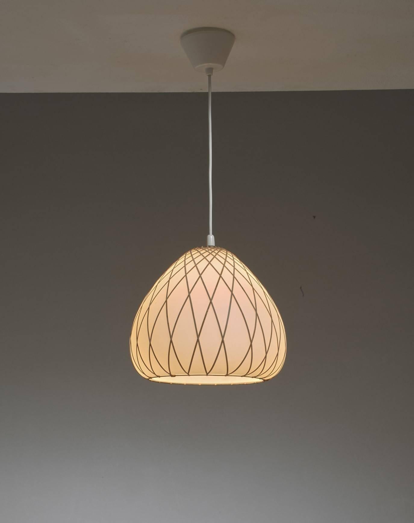 An opaline glass pendant with rattan woven around it in a geometric pattern. In style this pendant is remiscent to the work of Lisa Johansson Pape.
The combination of materials makes the lamp work great in a natural or Campagne style setting.

*