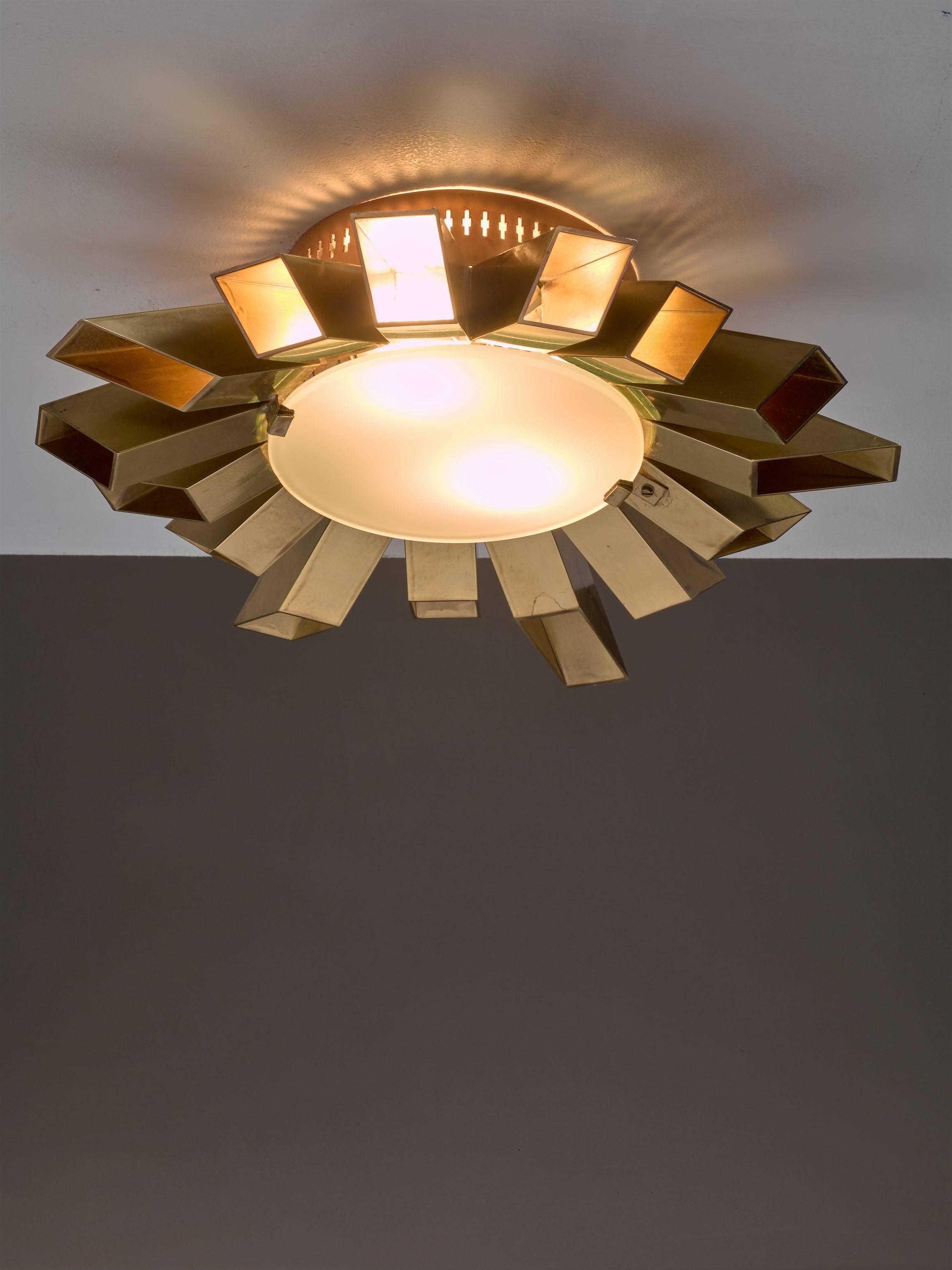 An exeptional Swedish Mid-Century flush mount 'sunburst' ceiling lamp, made of 15 brass elements that spread outward from the centre, like rays of sunshine. The lamp has two light bulbs and a double opaline glass diffuser in the centre.
Iit gives a