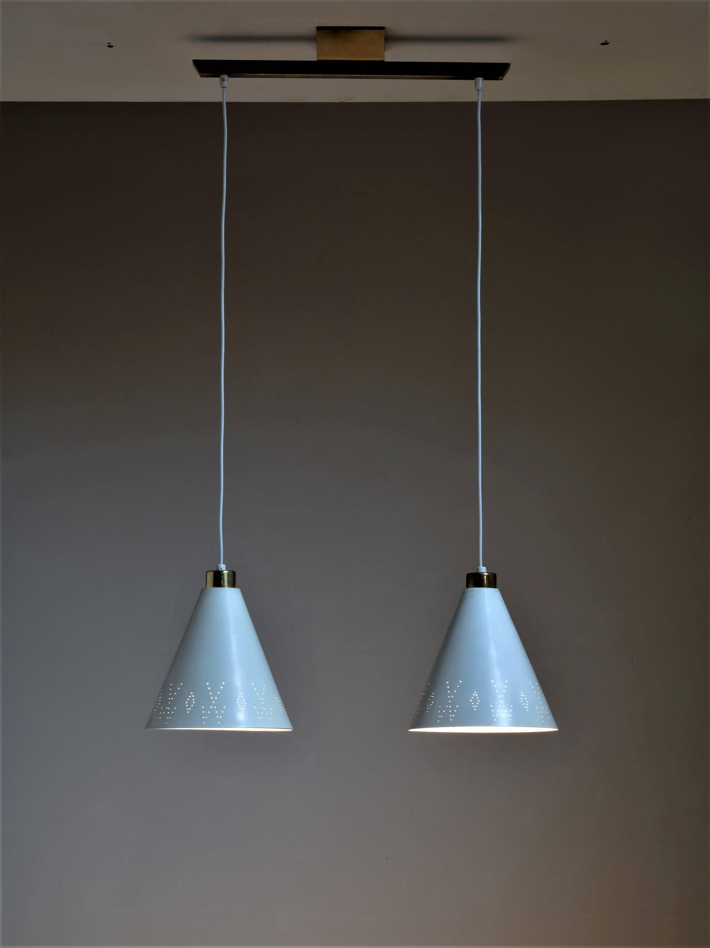 A rare ‘model K2-60’ pendant by Paavo Tynell with two shades hanging from a rail. The metal shades are painted white and have the typical Tynell pinhole perforations, here in a less typical geometric pattern.