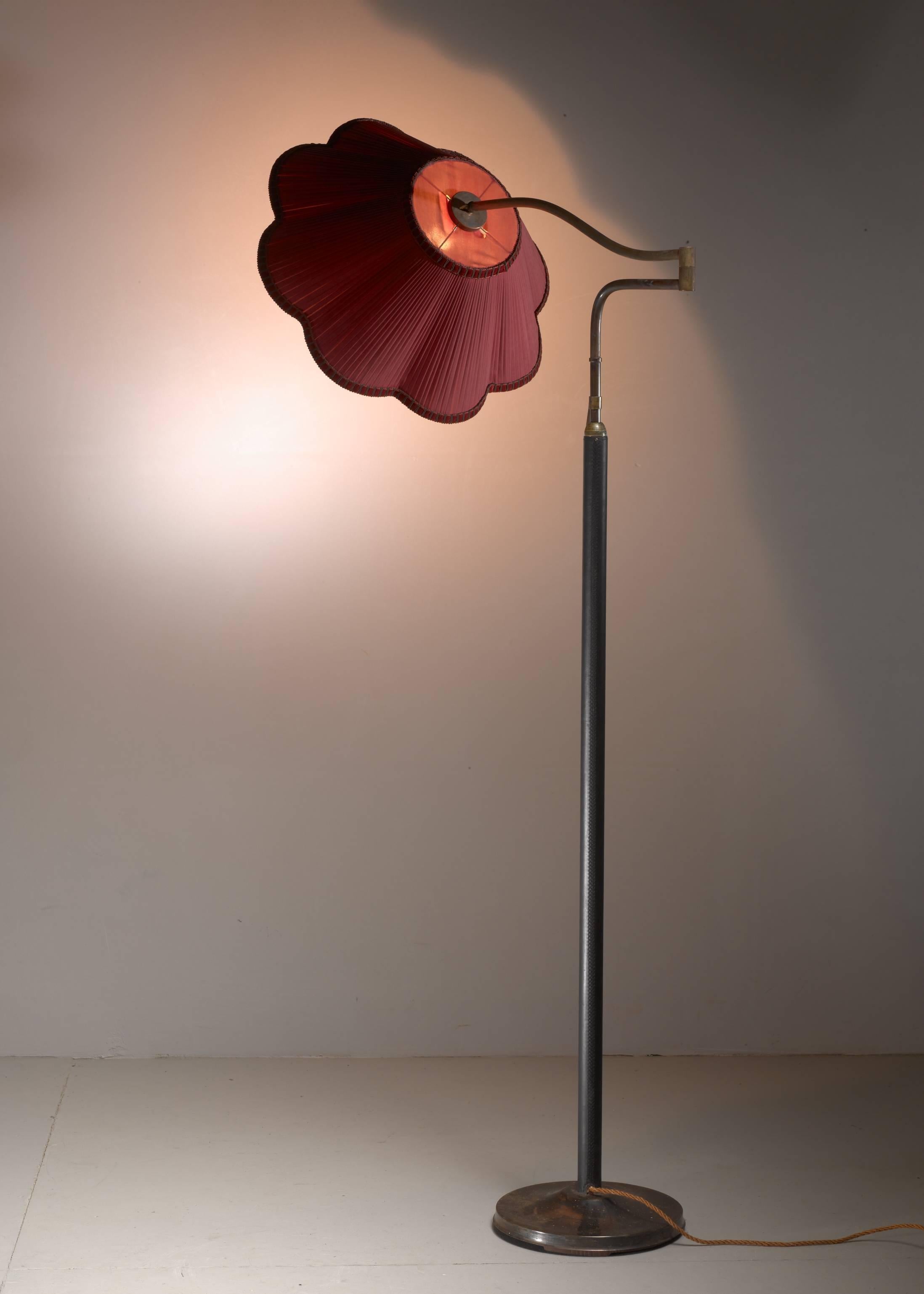 An Austria floor lamp attributed to Josef Frank for J.T. Kalmar, Austria. The lamp has a brass base and a brass stem with wood veneer. The lamp has a swiveling brass arm with a fabric hood. The lamp is height-adjustable between 157 and 190 cm (62