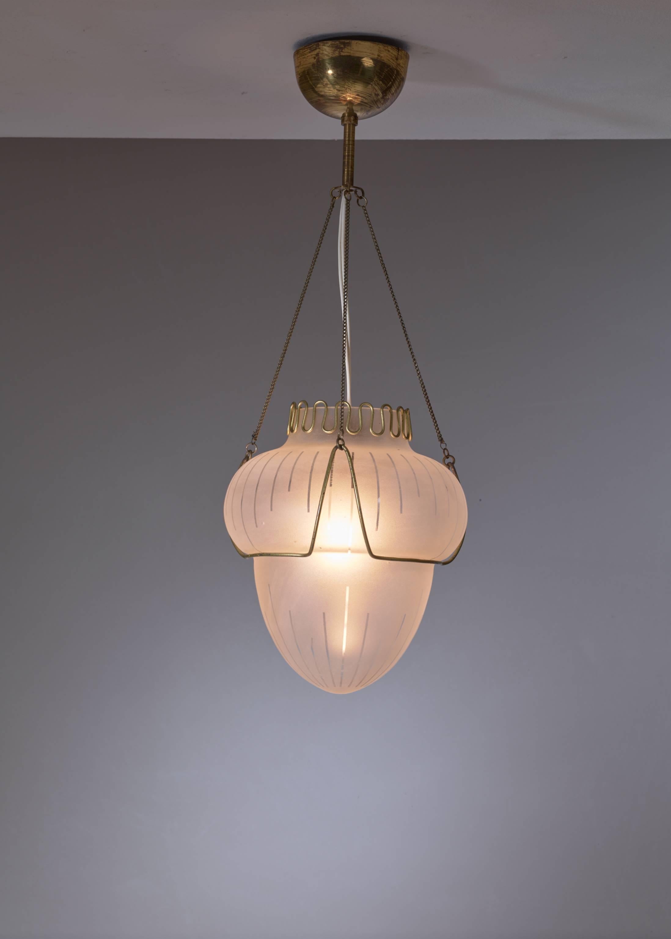 A Swedish pendant lamp made of a frosted glass shade with a striped pattern, hanging in a brass frame. The shade has a undulating brass decoration on top.
Beautiful classical pendant.

* This piece is offered to you by Bloomberry, Amsterdam *