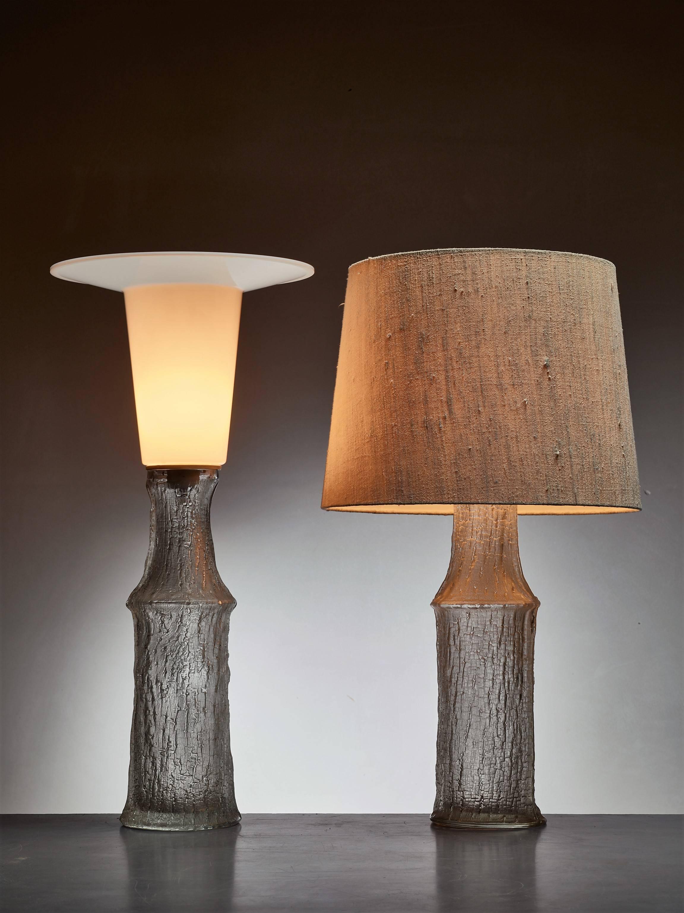A pair of table lamps by Timo Sarpaneva for Luxus. The lamps are made of molded Iittala glass with a plastic diffuser on top.

We have two original shades, each with different fabric. The original shades can be customized with a new fabric.

* This