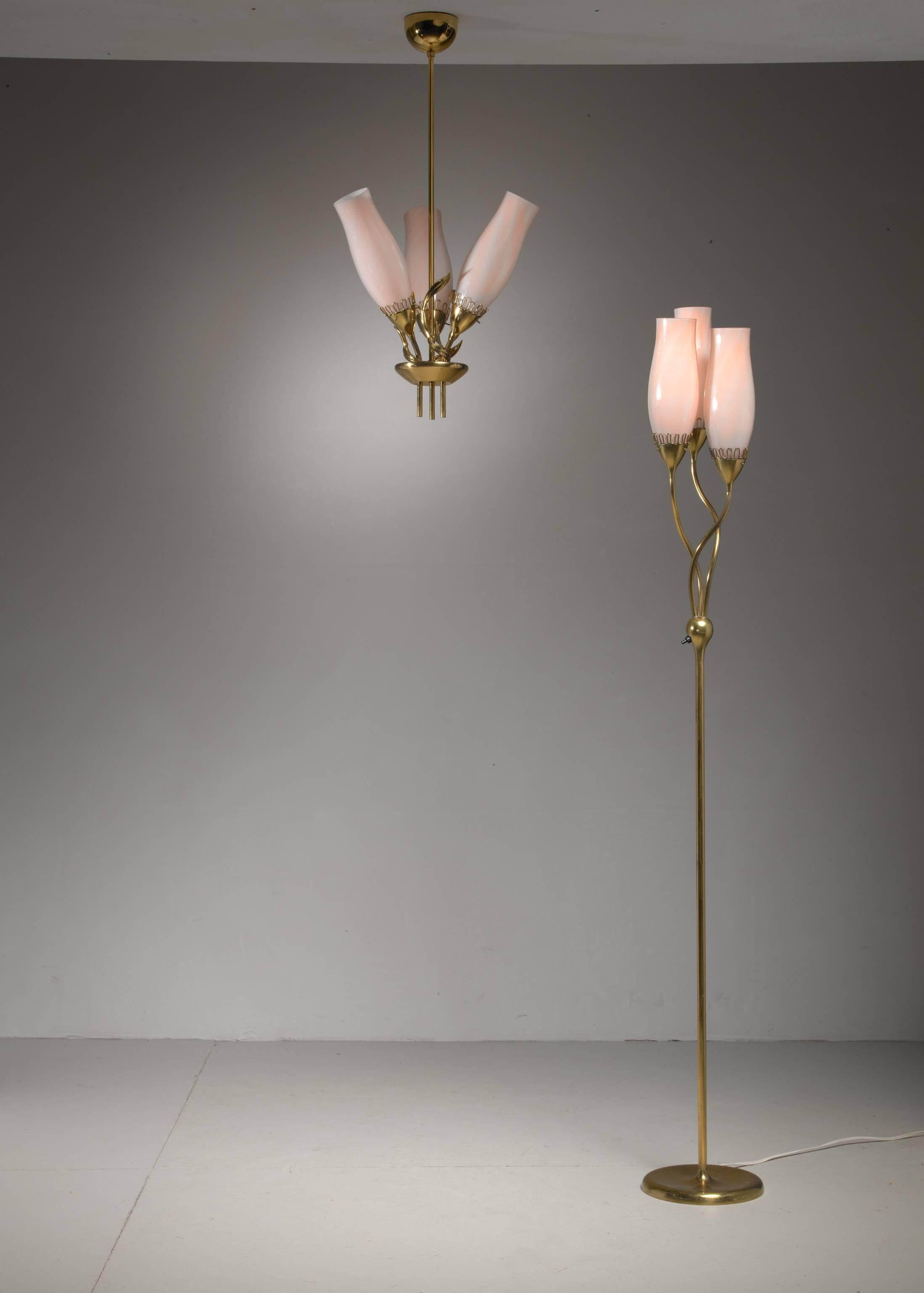 A rare model 51122 pendant and matching floor lamp by Paavo Tynell for Idman. Both lamps are made of brass with three glass shades in soft pink. The glass has two layers, white inside and pink outside.
The shades are held by a brass crown shaped