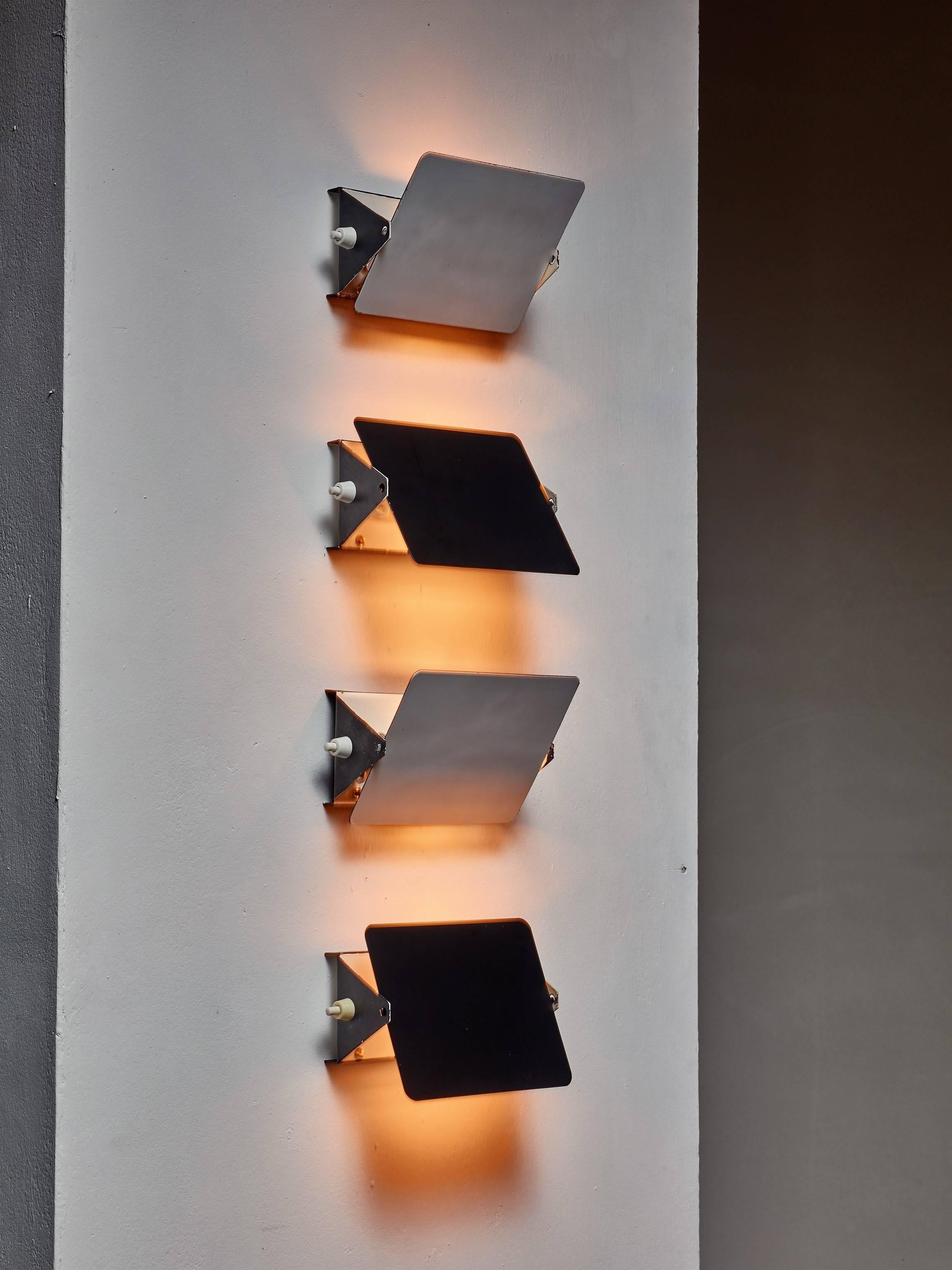 A set of four Charlotte Perriand CP1 wall appliques with an enameled metal adjustable deflector. One side of the deflector is white and the other is black. The lamps have an E14 fitting.

These items are from the Arc 1600 ski resort in Les Arcs