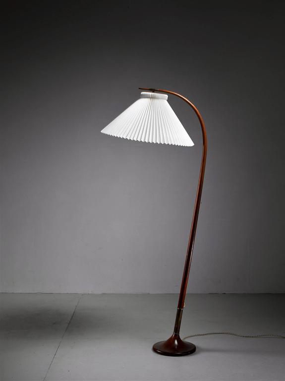 An elegant floor lamp by Danish designer Severin Hansen Jr. The lamp is made of a curved, stained beech frame with brass elements at the foot and where the shade is connected to the frame. The lamp has a white pleated plastic shade by Le Klint. An