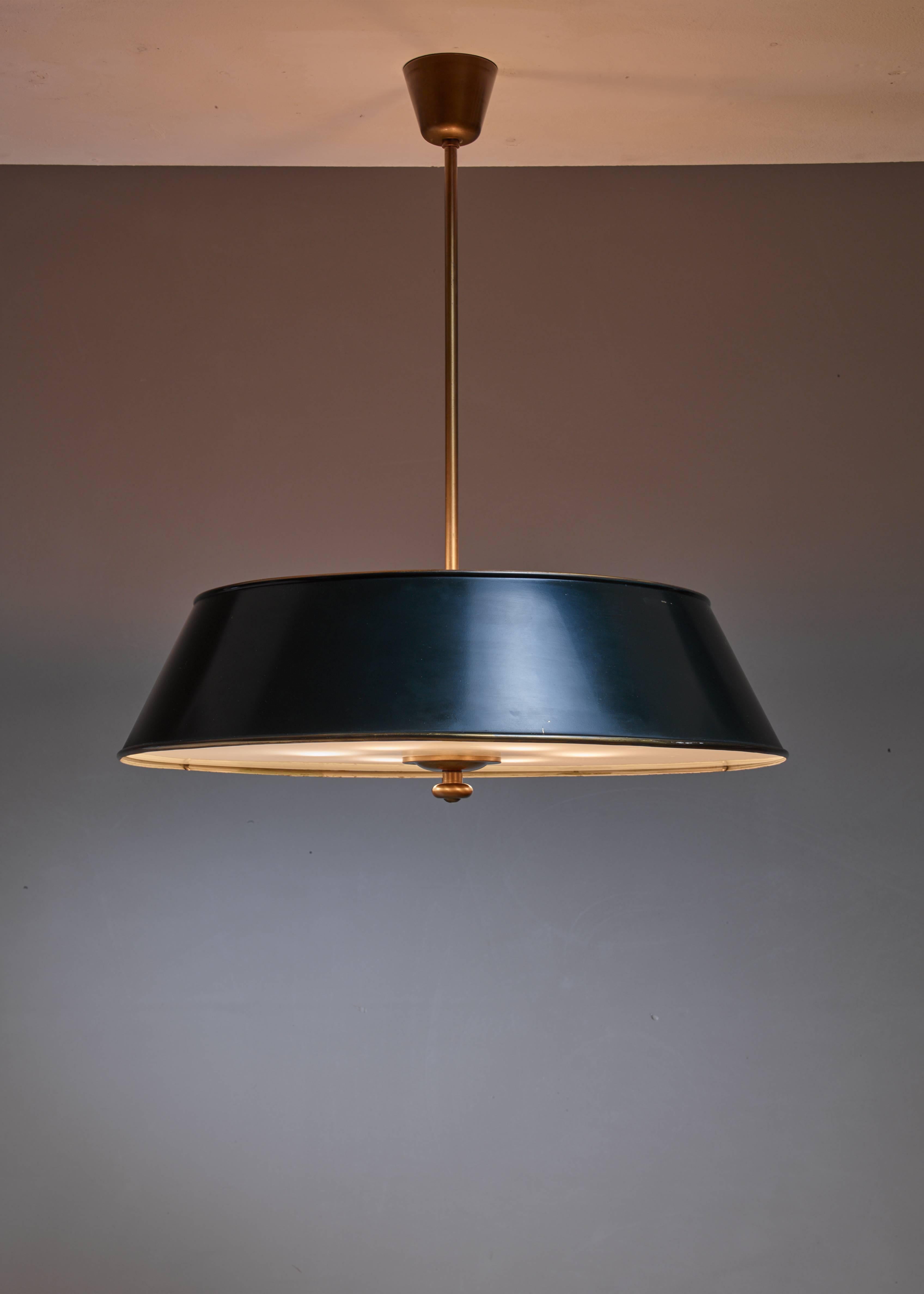 A Modernist pendant by Swedish designer and sculpture Harald Notini. The lamp is made of dark green or nearly black lacquered metal and a brass stem. The lamp has a frosted glass diffuser. It has light bulbs inside and on top of the shade.

    