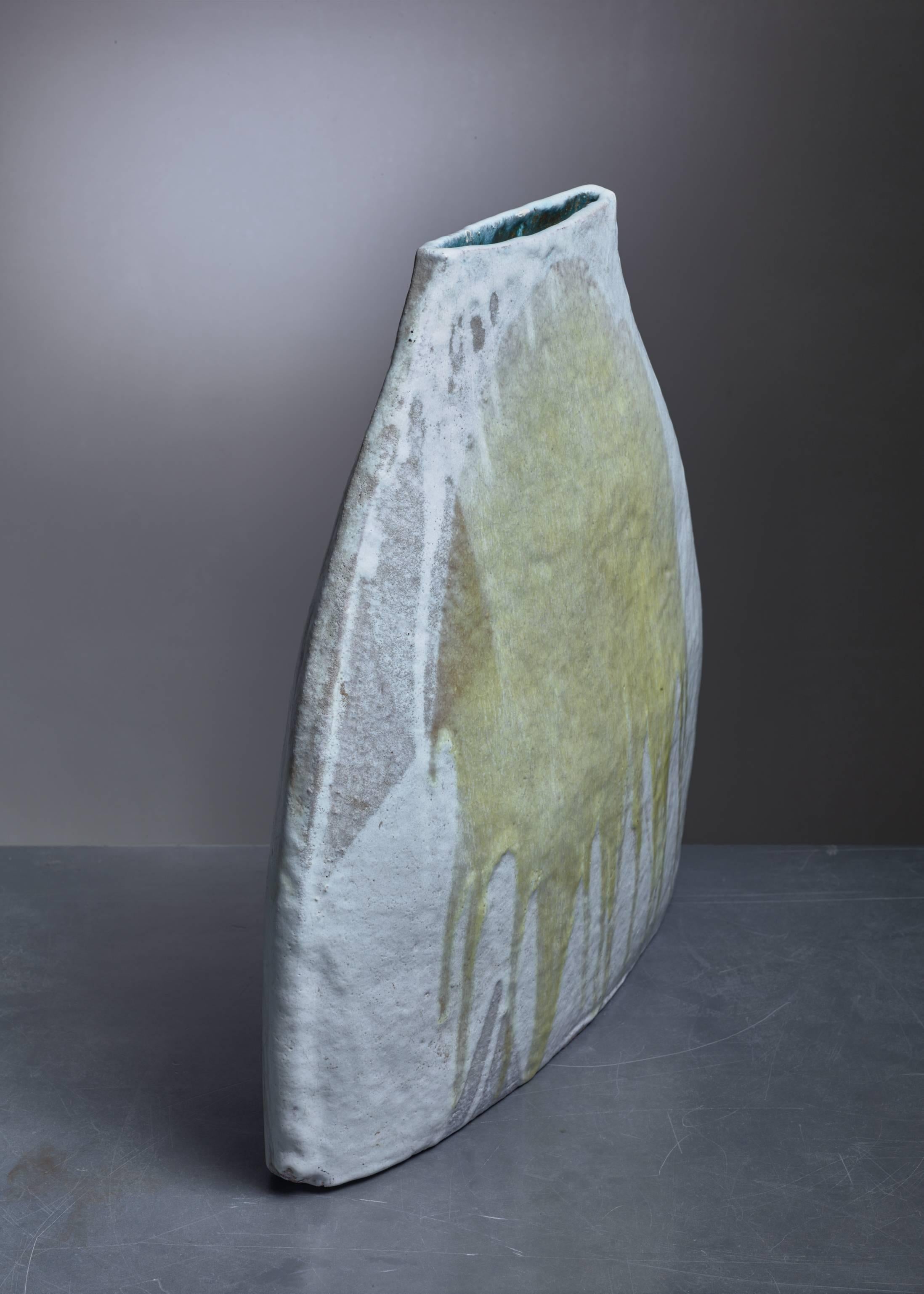 A high and thin sculptural vase with an abstract decoration in yellow and grey.
This piece was made by a Belgian ceramist who specializes in garden ceramics.
