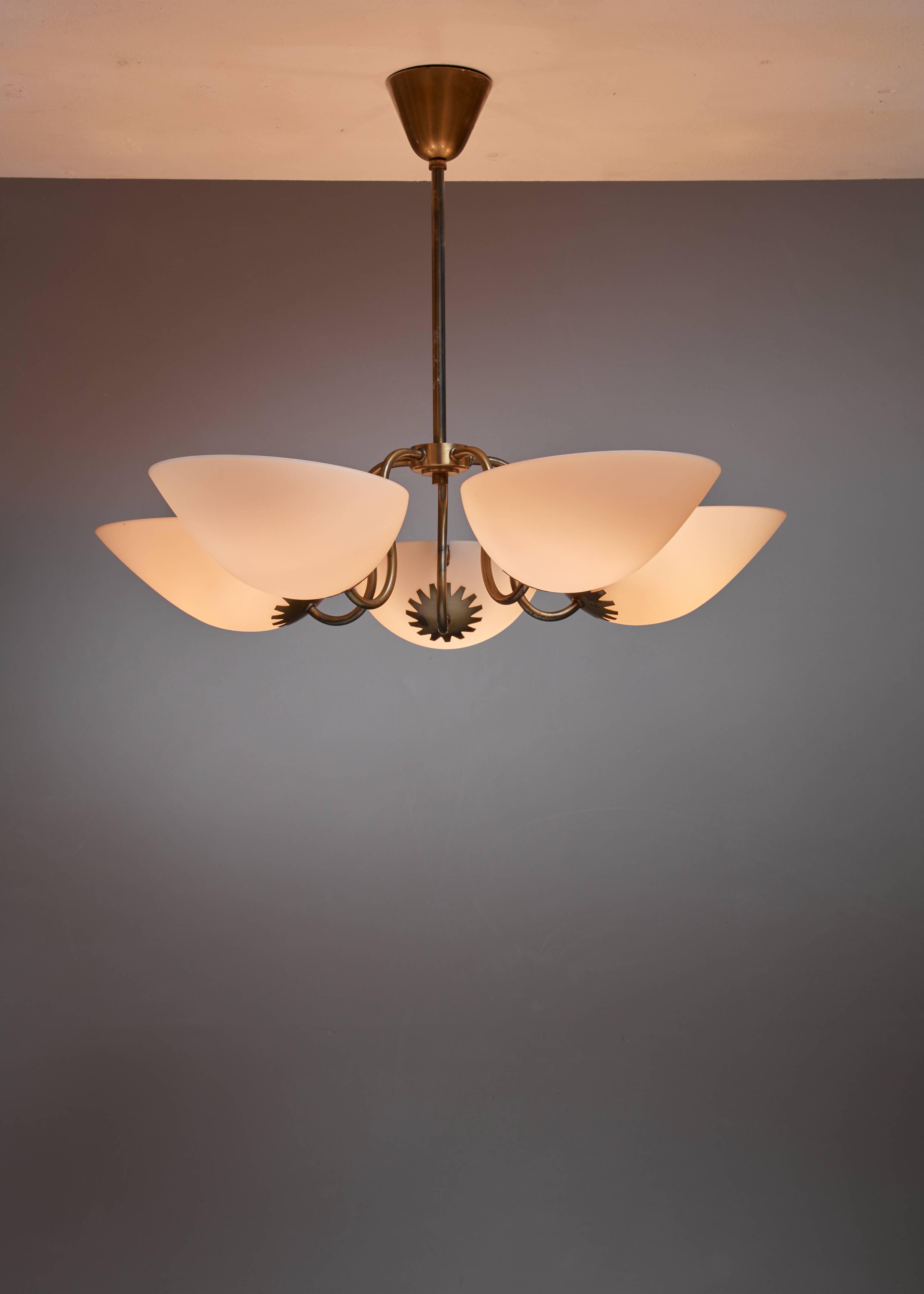 A Swedish chandelier with five brass arms, each holding an opaline glass shade.

The lamp is reminiscent of the designs of Bertil Brisborg. Total drop can de adjusted to your requirements.
