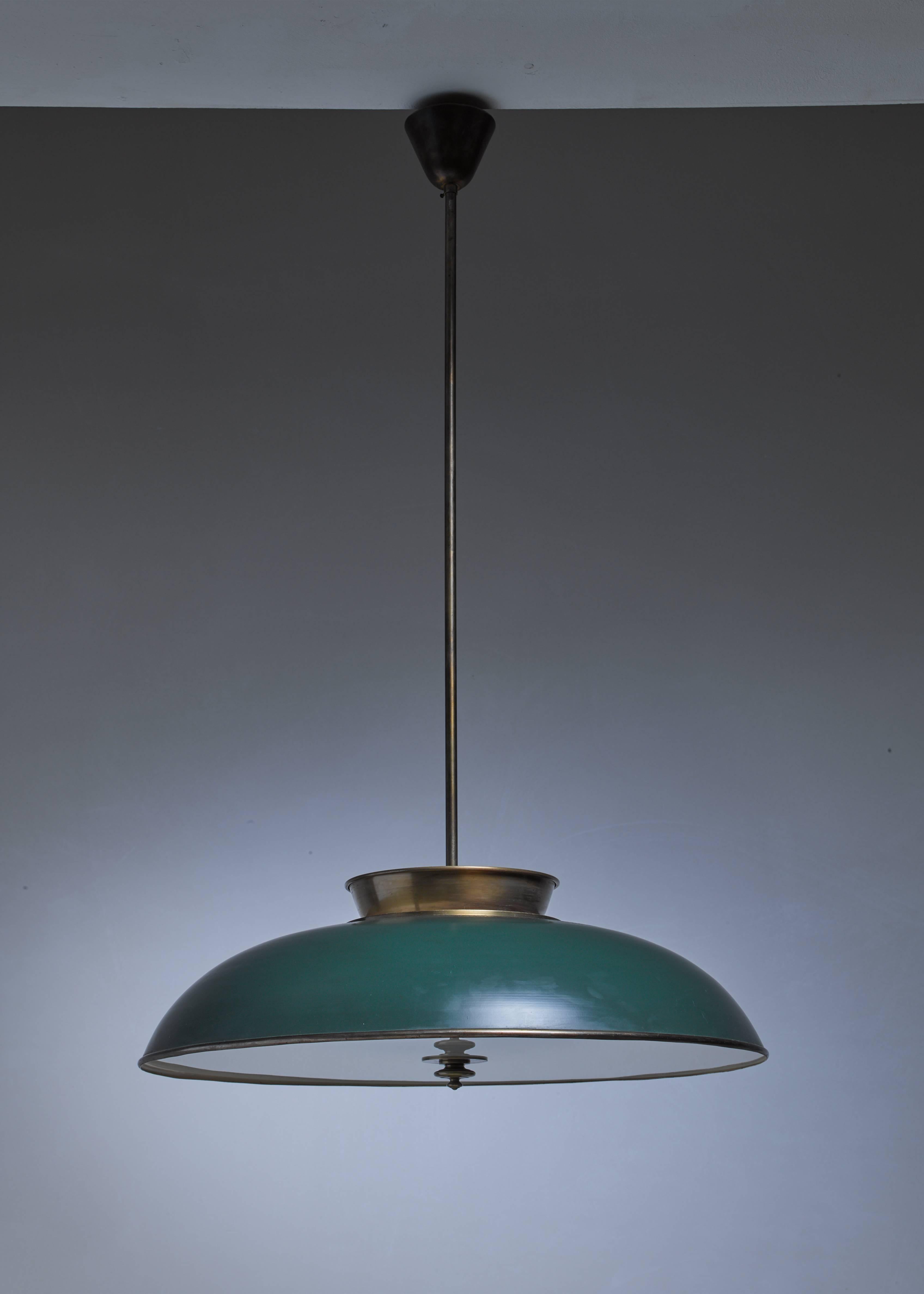 An early Modernist Swedish pendant lamp by Harald Notini made of brass with a frosted glass diffuser. Part of the shade is lacquered green and the lamp hangs from a long brass stem. The lamp has six-light bulbs inside and two on top of the lamp.
