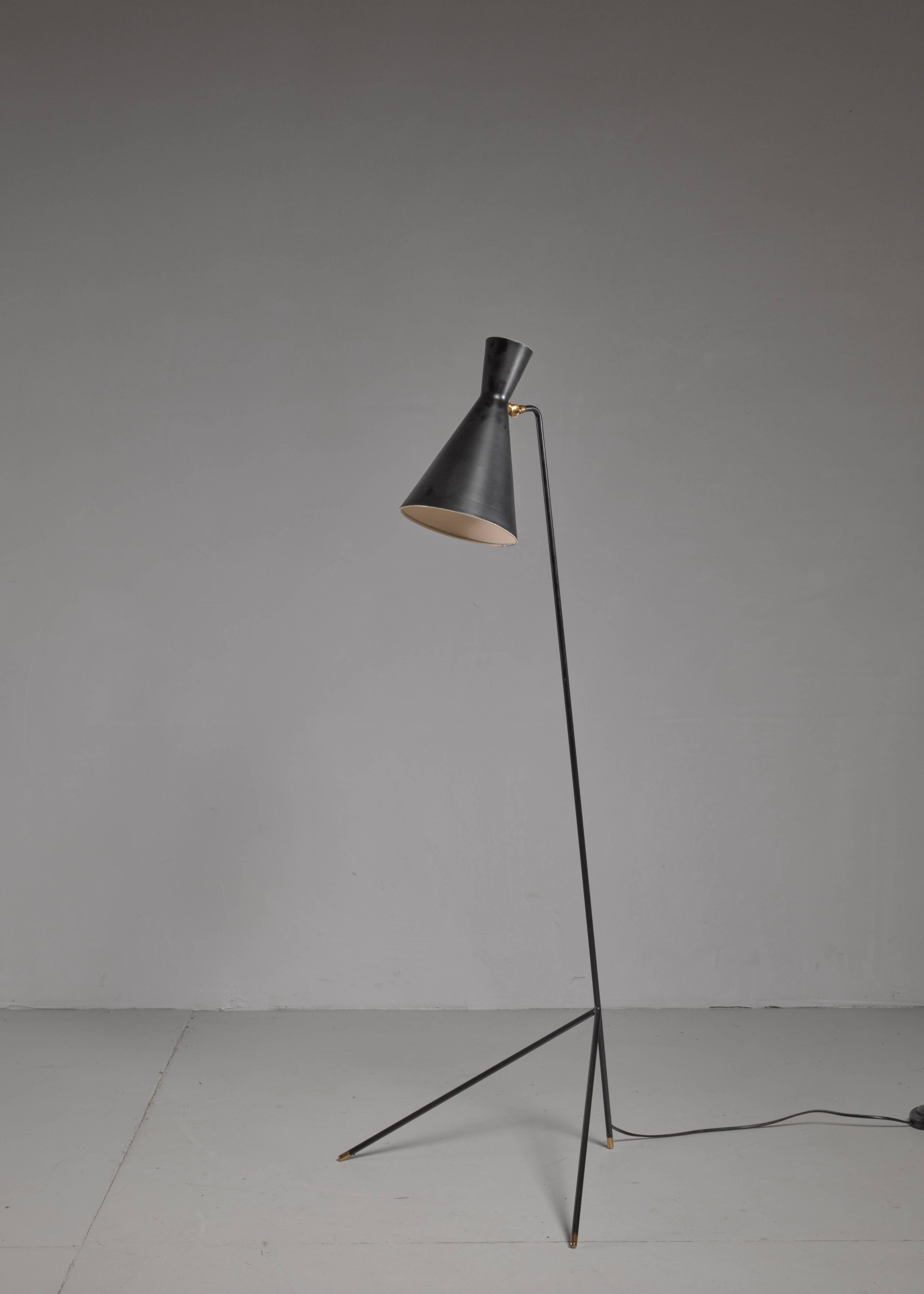 A Svend Aage Holm Sorensen floor lamp, made of black lacquered metal with brass details. The lamp has an adjustable diabolo shaped hood.