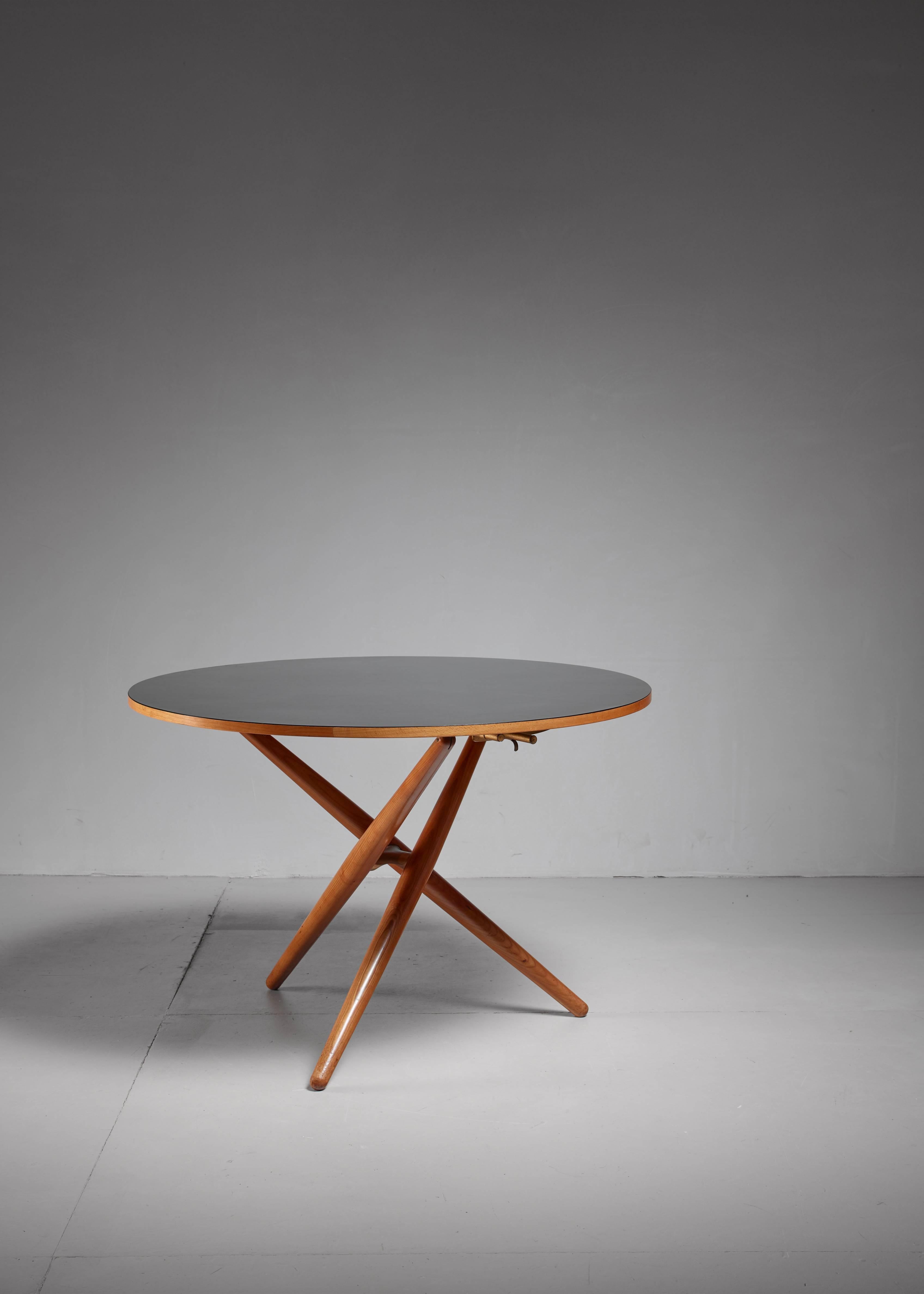 An early edition height-adjustable oak table, designed by Jürg Bally for Wohnhilfe, Switzerland in 1951. The black formica top rests on three crossed legs. 
* This piece is offered to you by Bloomberry, Amsterdam *

The table has the height
