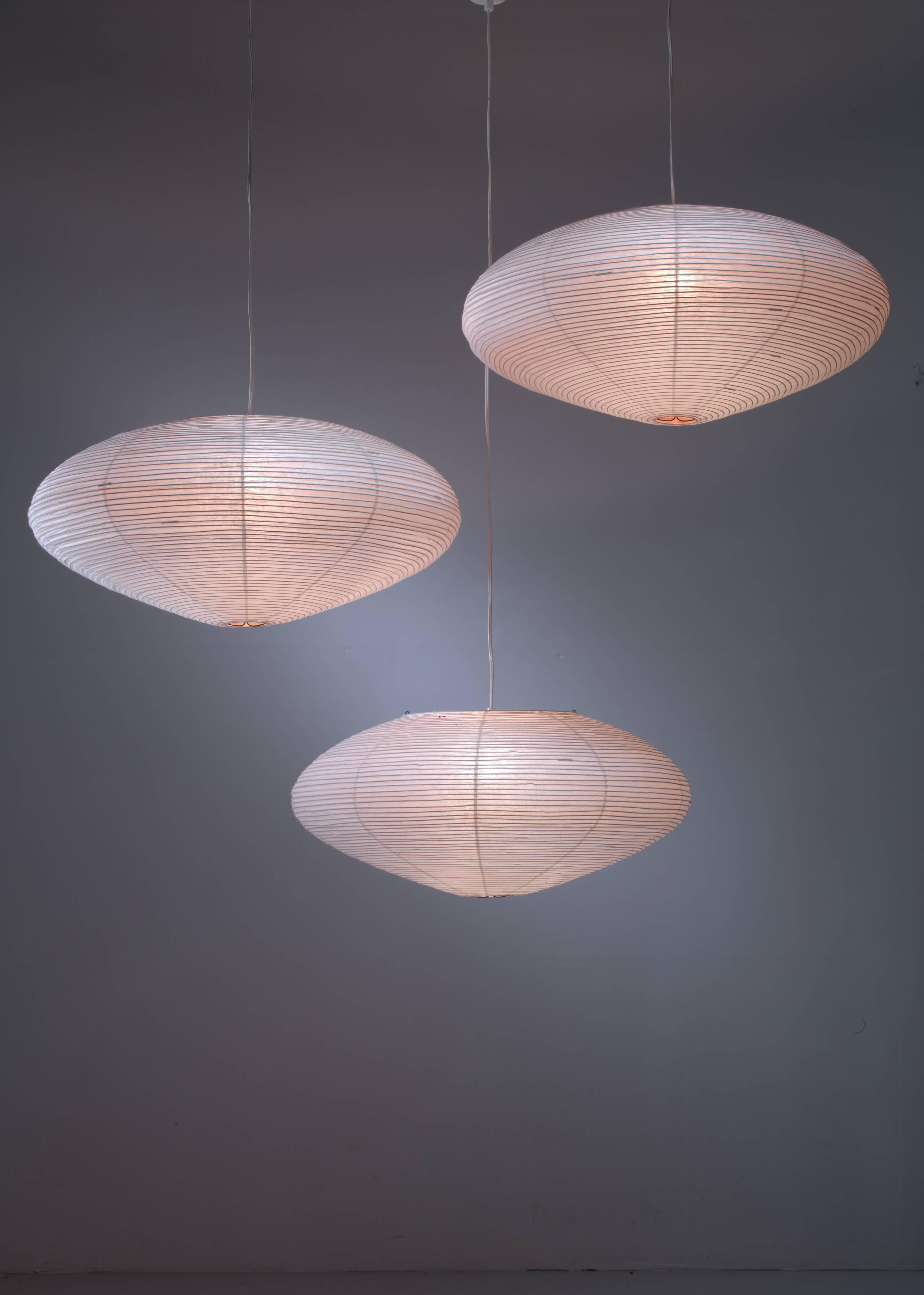 A set of three early handmade Isamu Noguchi A21 paper pendants for Akari, branded with the original logo. The lanterns are a beautiful combination of Japanese handcraft with modernism.

All three in perfect condition and stamped. Dimensions are of