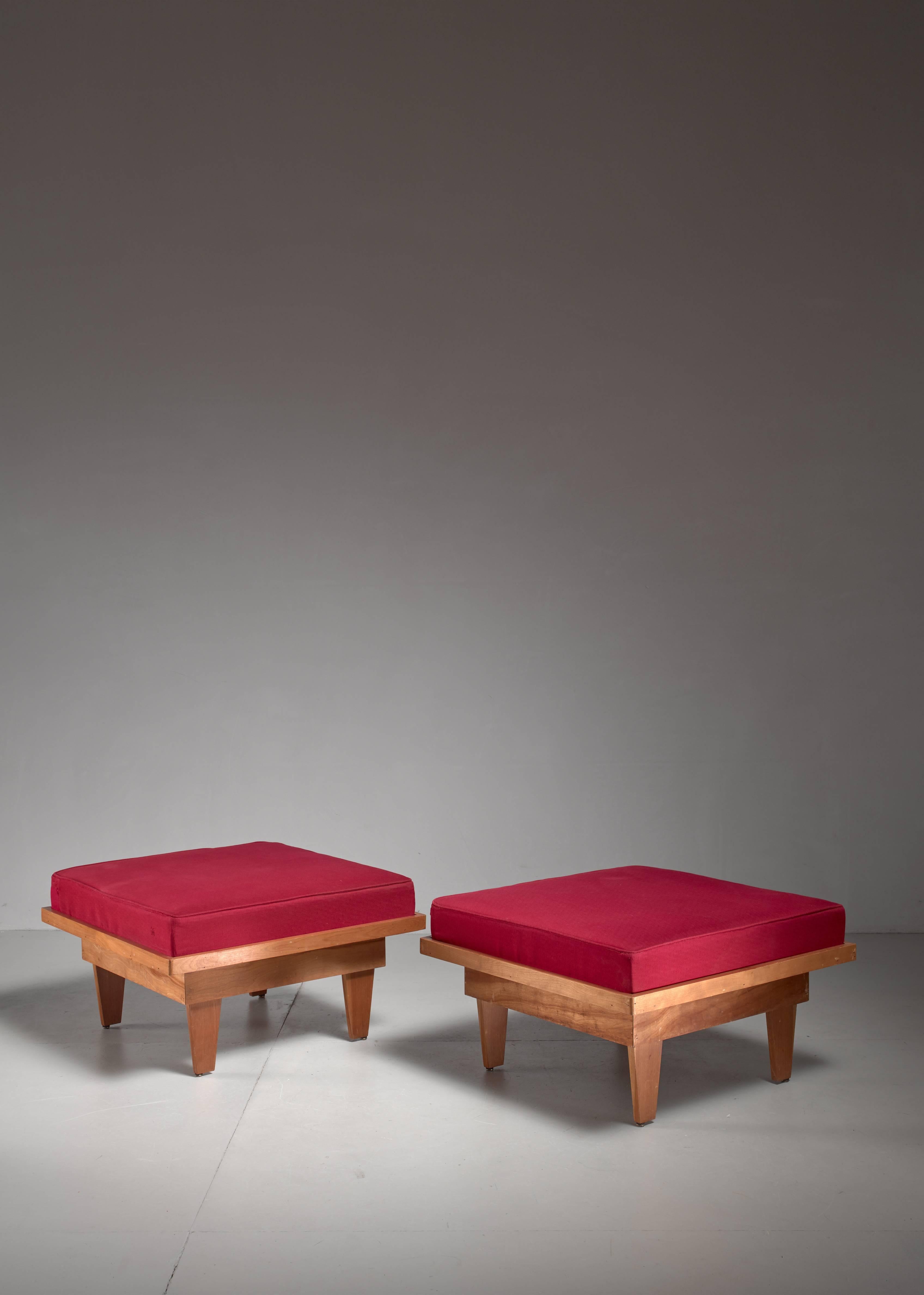 A pair of studio crafted ottomans. This midcentury American set is made of plywood and cushions with a red fabric upholstery.