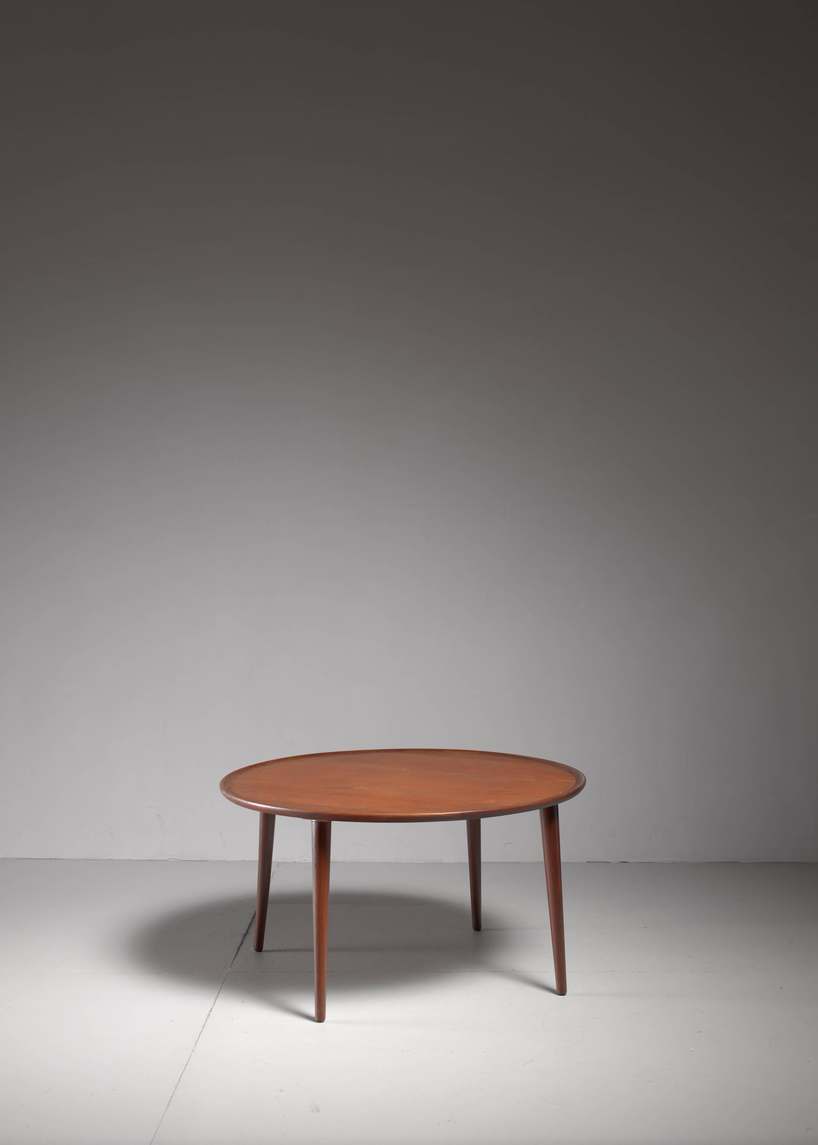 A round teak coffee table by a yet unrevealed Danish cabinet maker. The small upward edges shows the skillfulness of the maker. At first sight it resembles the work of Peter Hvidt, but this is of another quality.

 The light tapering legs enhance
