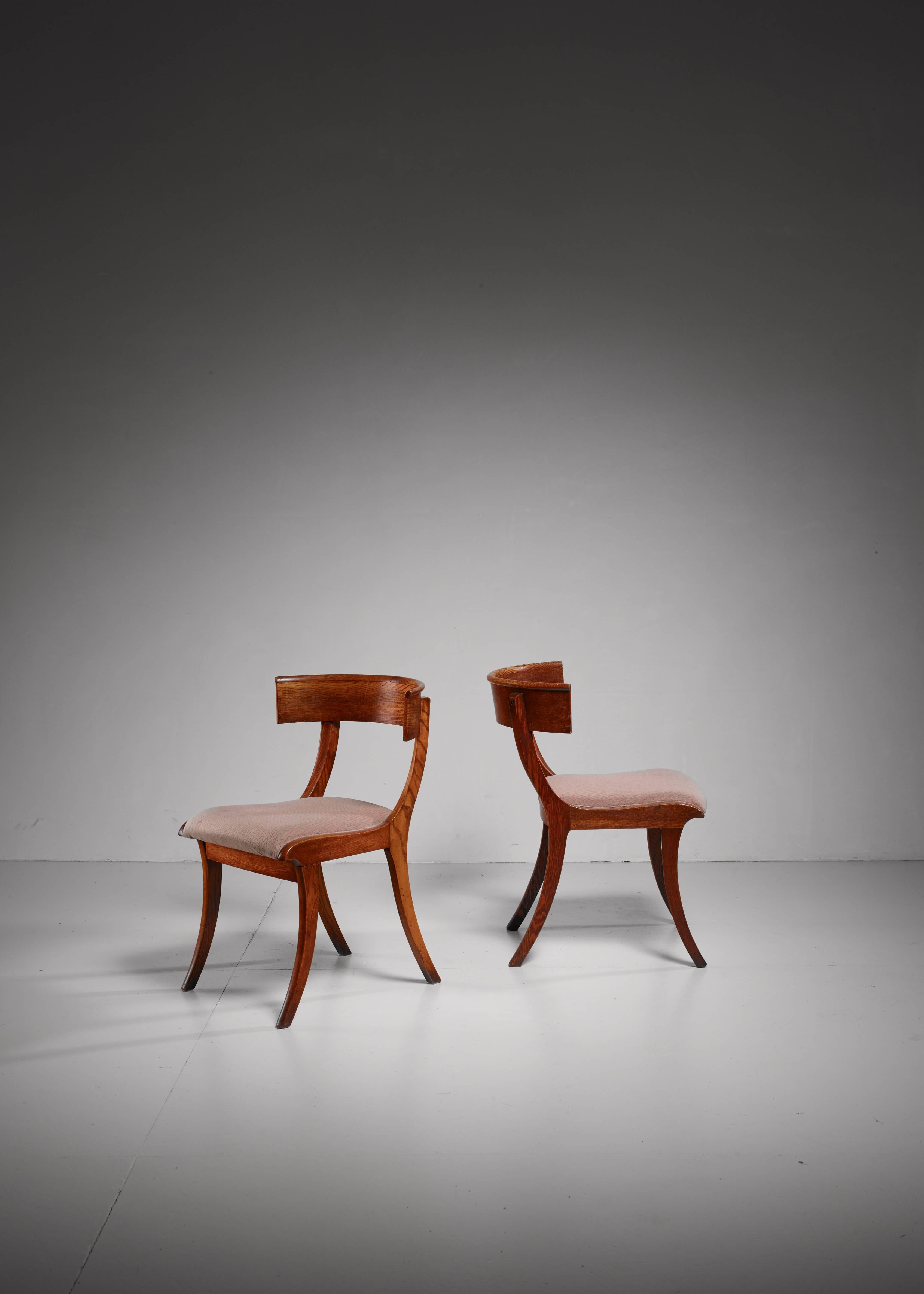 A pair of oak Danish Klismos chairs with a fabric upholstery in old pink with a geometric pattern.

The design of the Klismos chair, with its wide and curved backrest and sabre legs, can be traced back to Ancient Greece (5th century BCE). Elegant