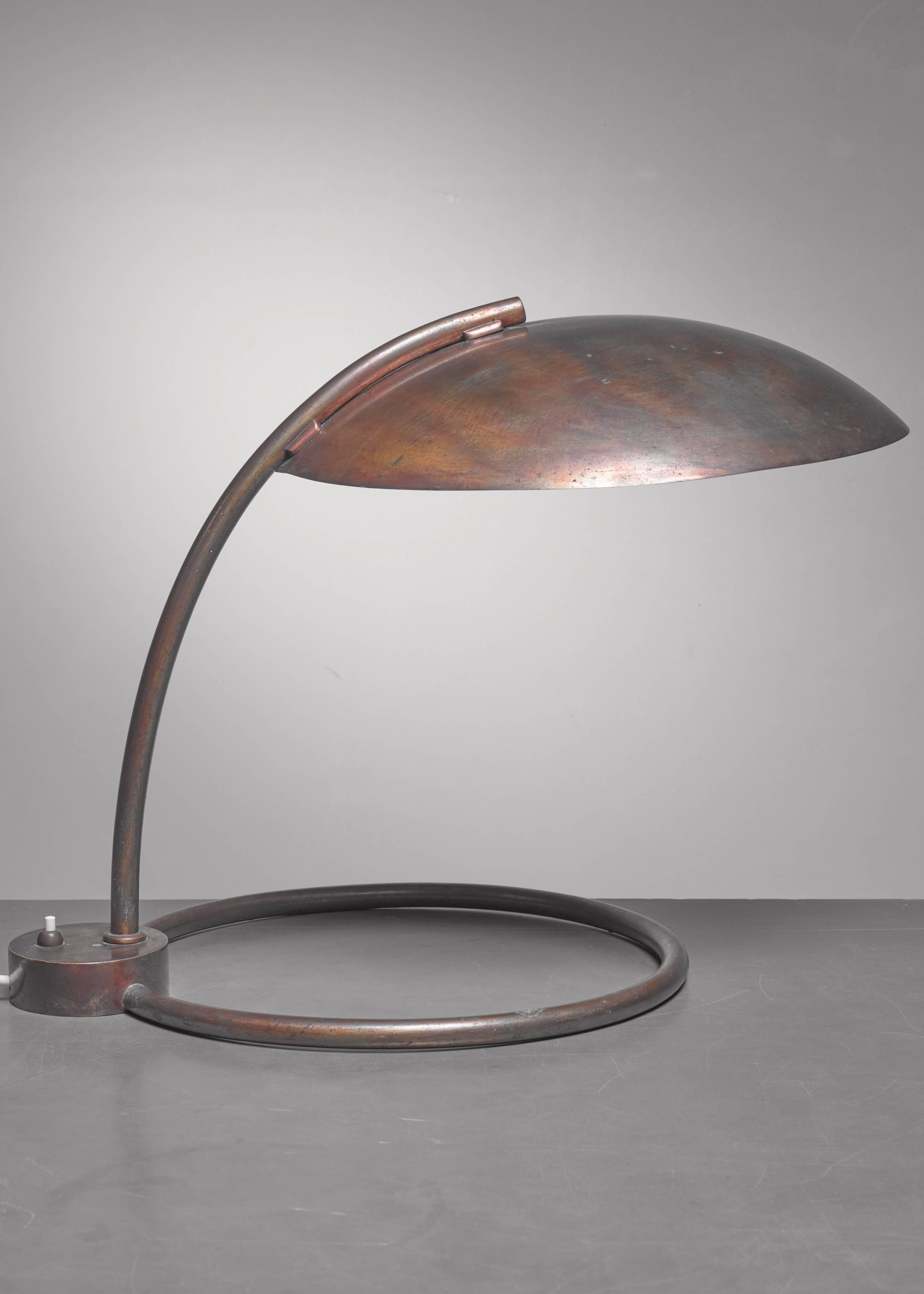 A 1940s heavy brass Italian table lamp standing on a large hoop base. The switch is integrated in the hoop. 
 