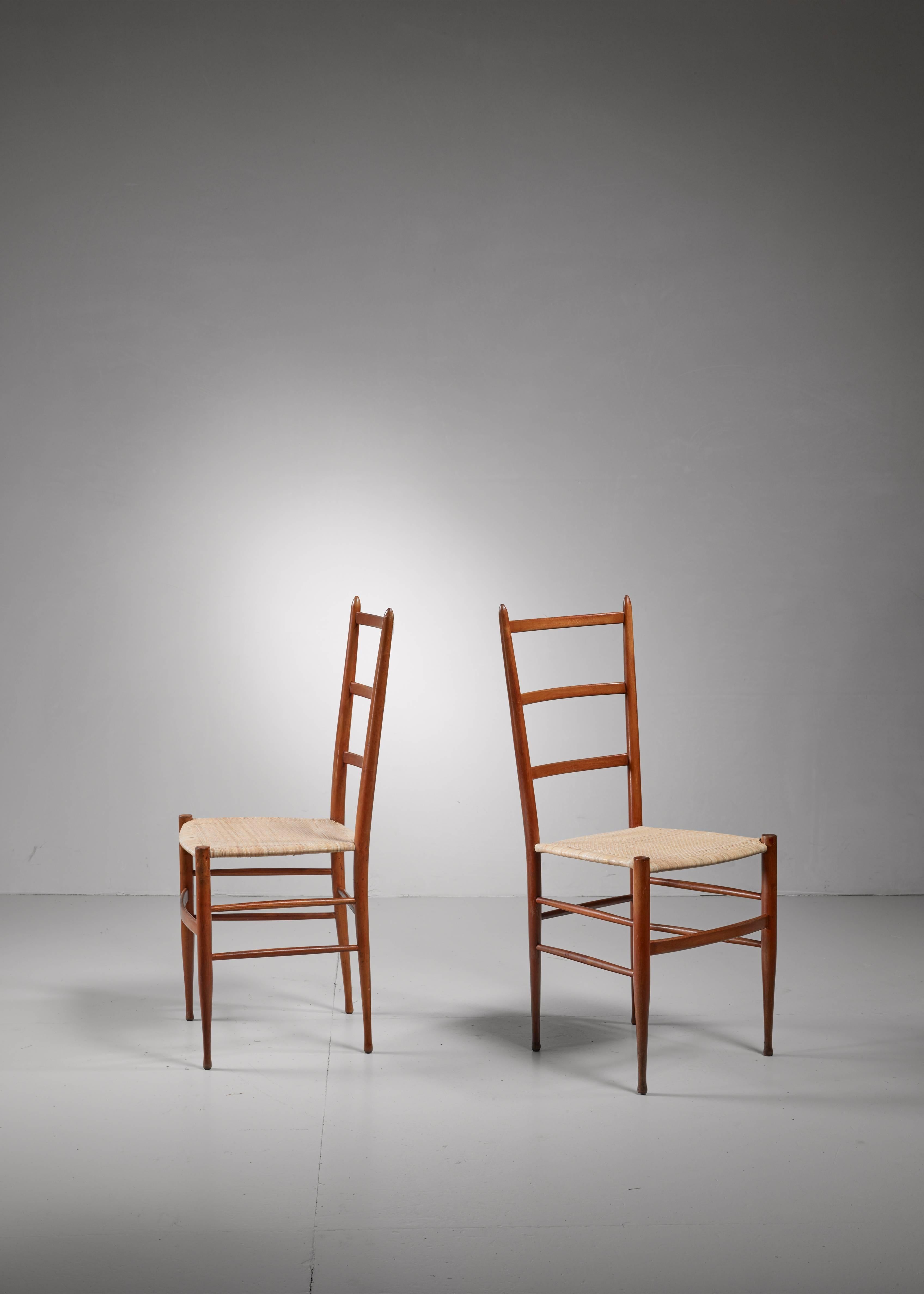 A pair of wooden Chiavari chairs with a woven cane seating.The chairs have been professionally reupholstered.

The slim and light chairs from Chiavari date back to 1807 and were the inspiration for Gio Ponti's 'superleggera' chair.