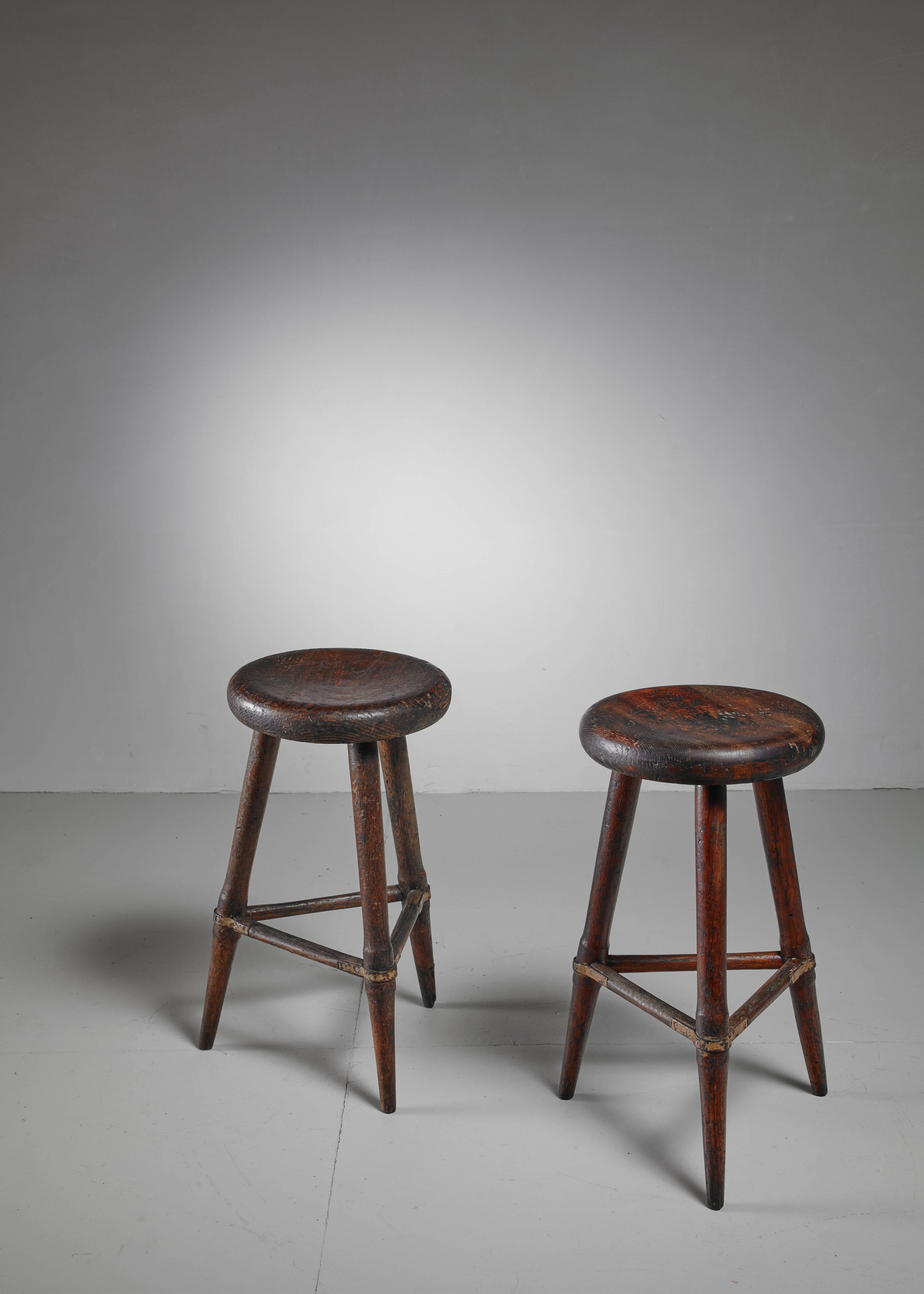 A pair of high Scandinavian wooden tripod stools. The iron in combination with the heavy patina of the wood gives these pieces a beautiful, rugged look. The three legs are held together with wooden dowels with wonderful iron connections.
