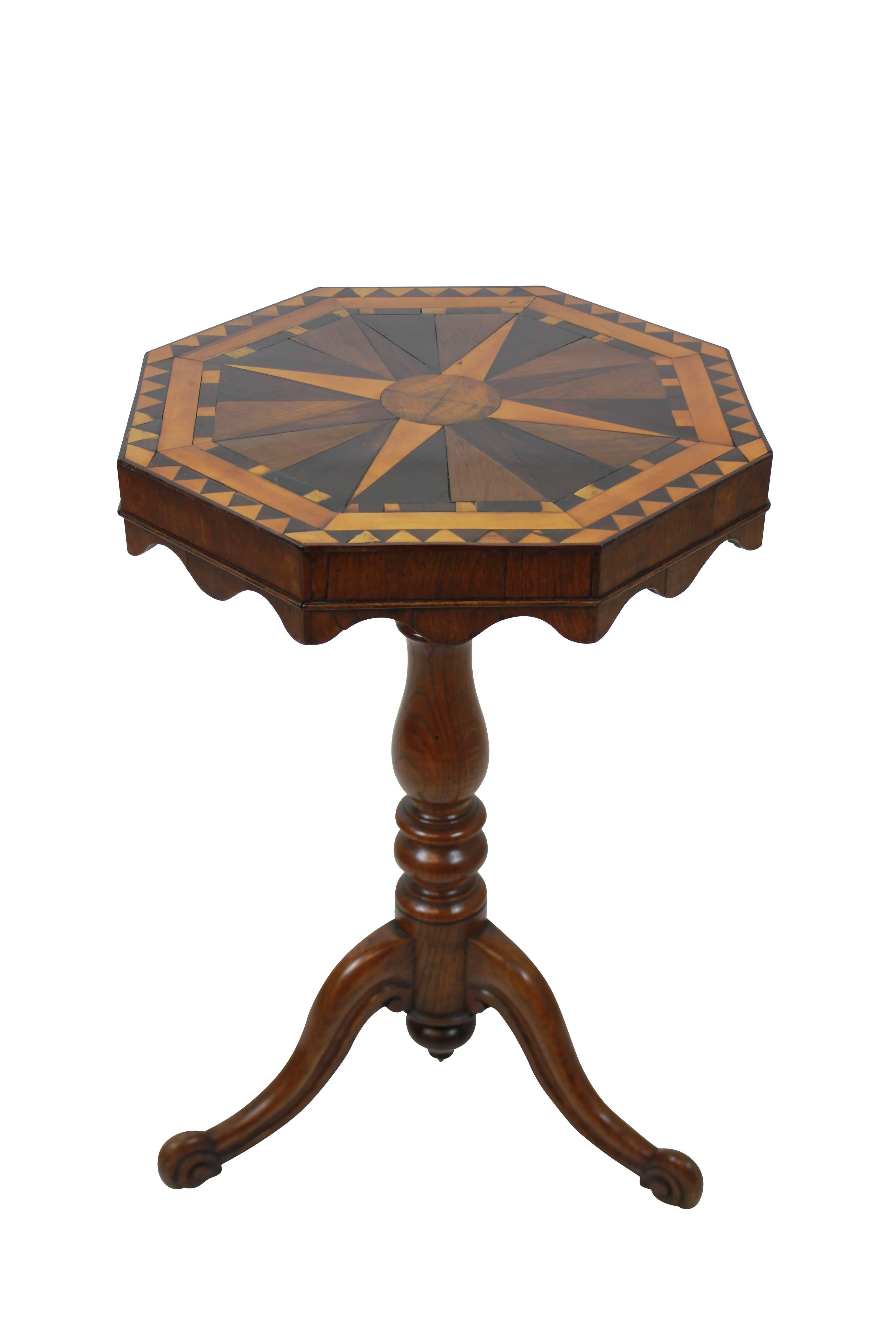 An English pedestal tilt-top table in elm with a fine geometric marquetry top in various English woods depicting a globe and compass. The turned tripod base supporting a tilt top with scalloped apron with original latch.
 