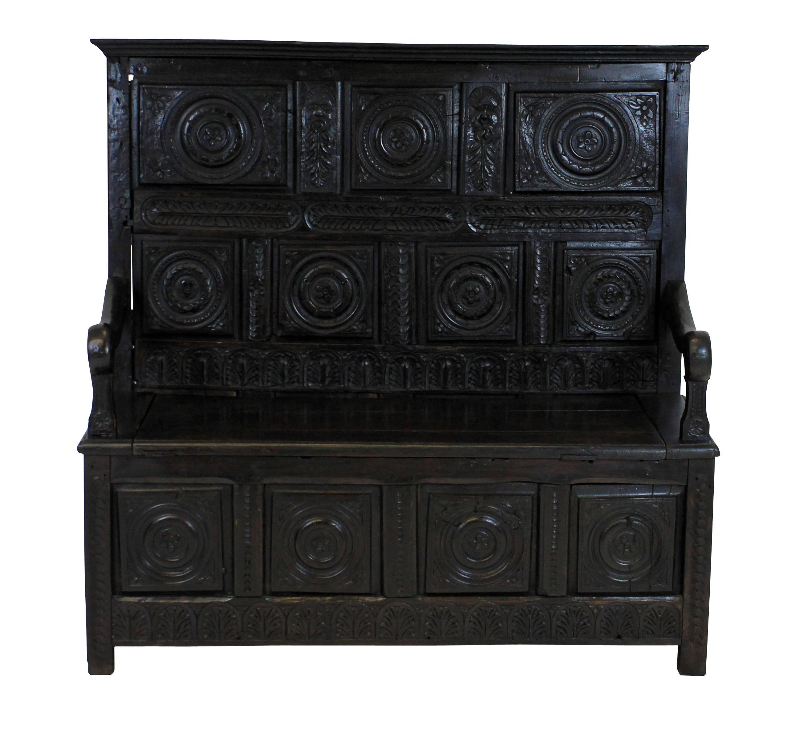 An English 17th century carved oak settle. Each panel depicting foliage and faces. There are some later restorations, but it is essentially original.
 